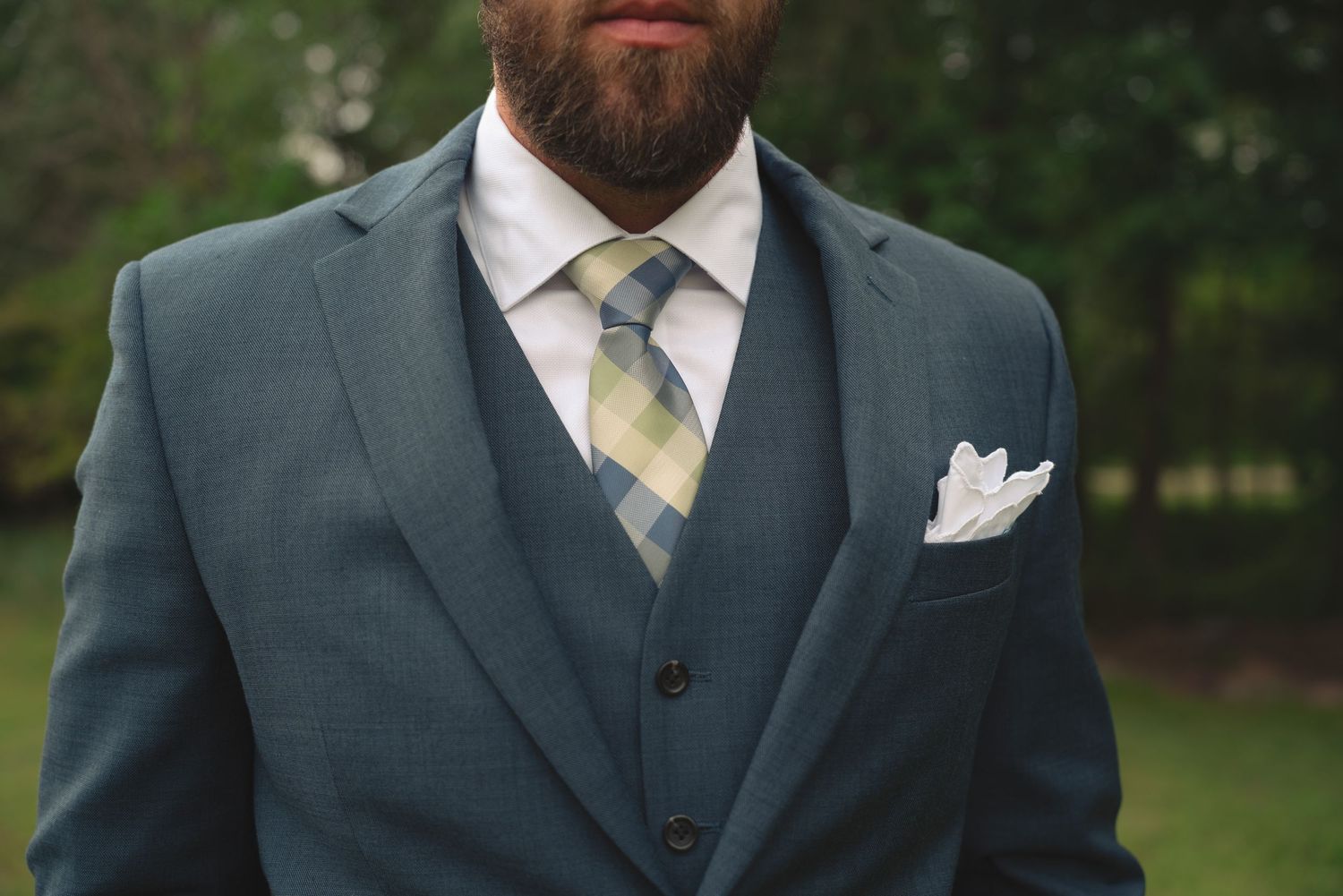 Detail shot of groom's formal attire with navy suit and striped tie.