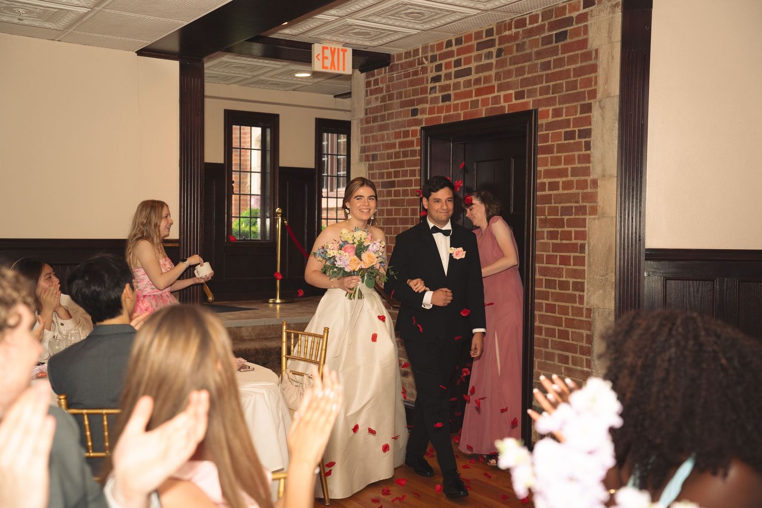 Wedding party entrance at indoor reception with guests clapping and celebrating.