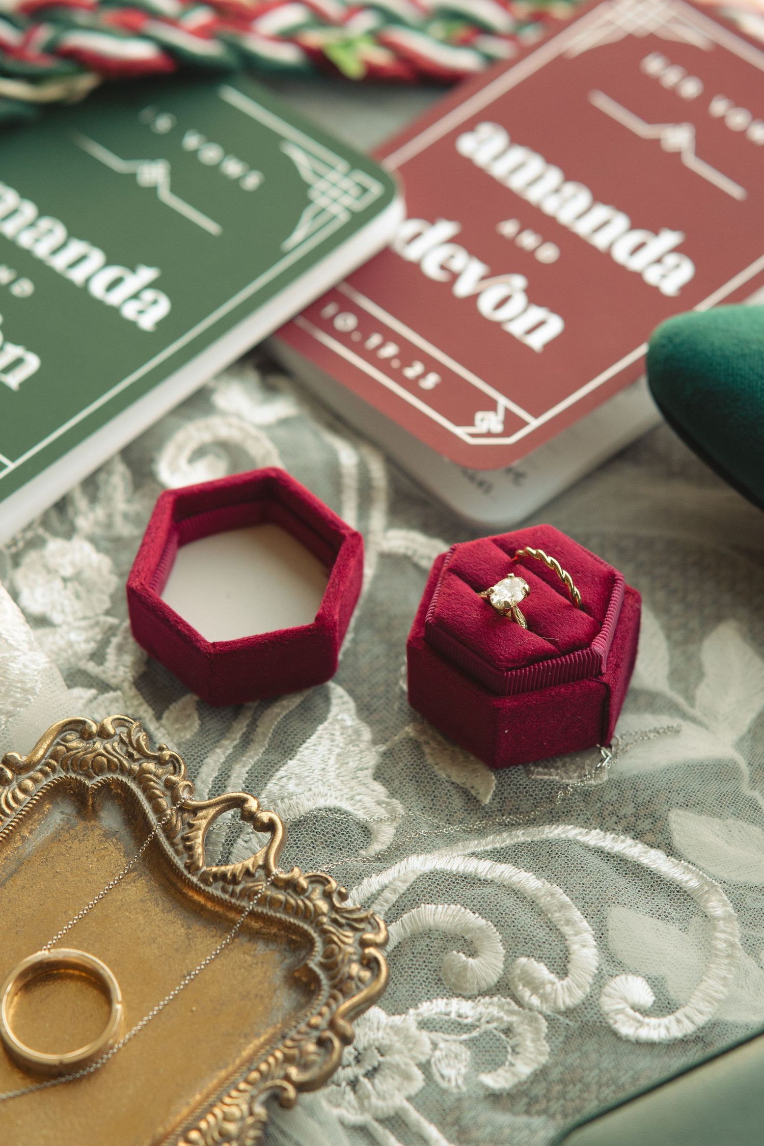 Red velvet ring boxes and vintage-style jewelry displayed on decorative paper.