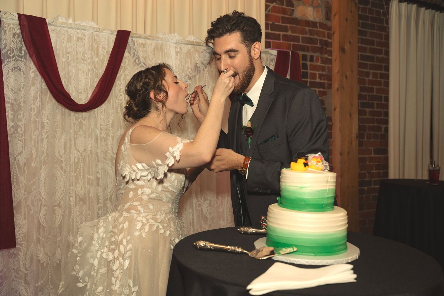 Wedding couple sharing a romantic moment near their green and white tiered cake.