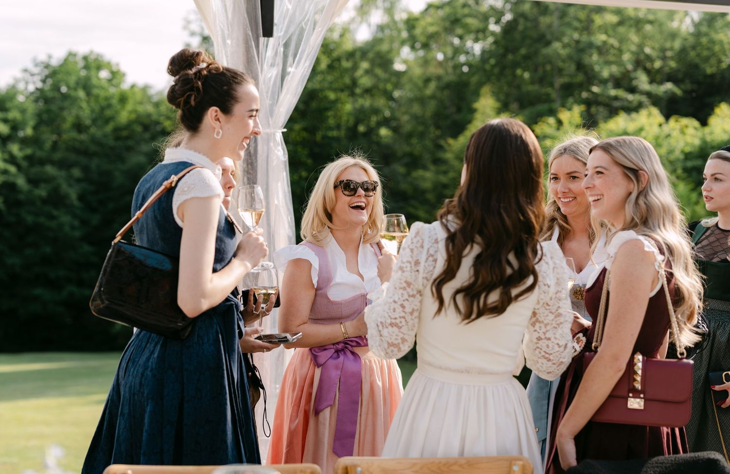 Outdoor wedding reception with guests mingling under string lights.