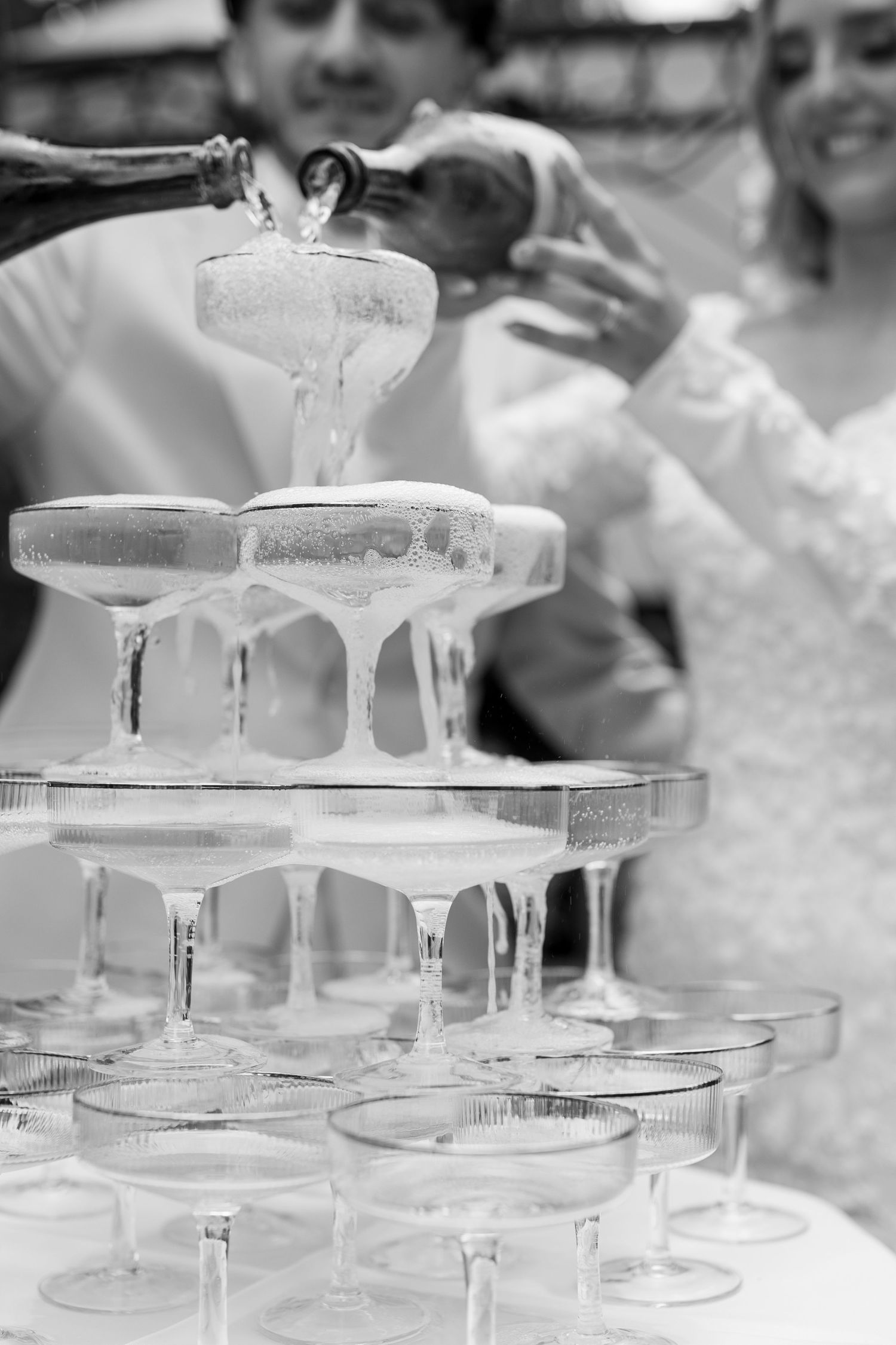 Elegant champagne tower with crystal glasses being filled at a wedding celebration.