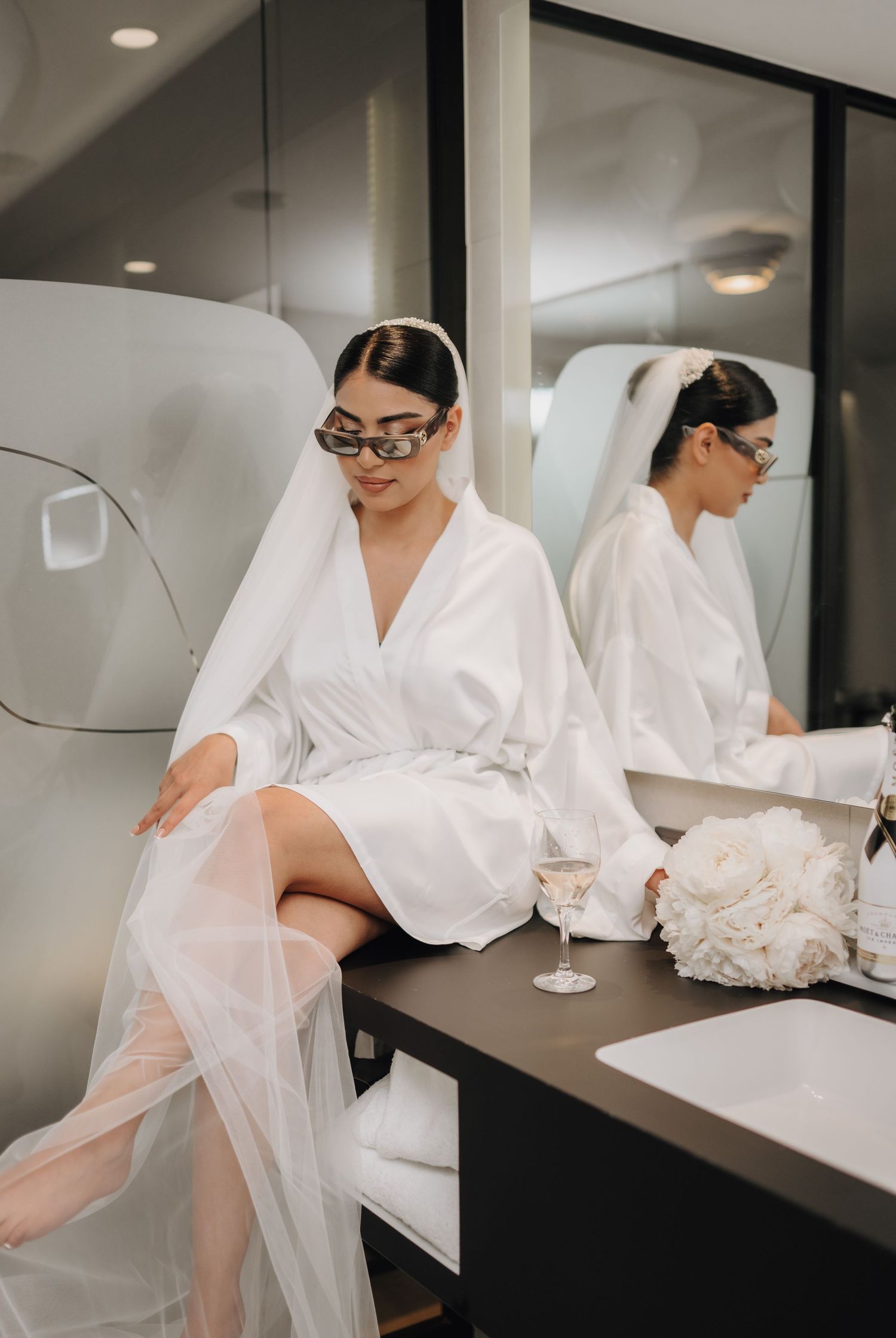 Elegant white robe and veil draped across modern furniture in preparation for wedding.