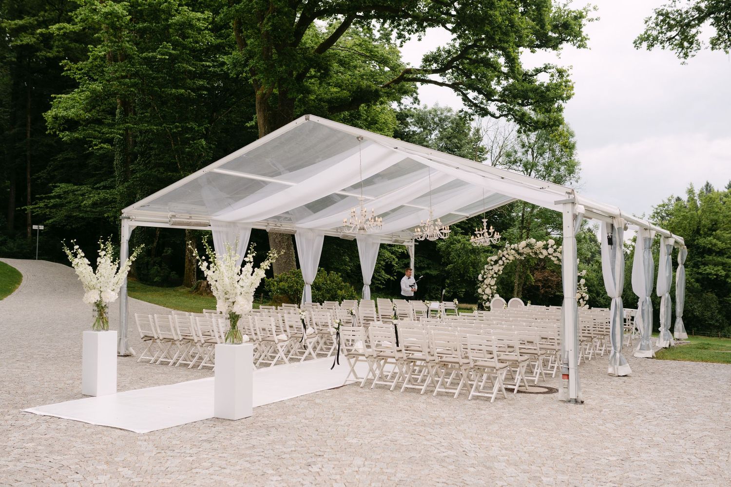 White tent pavilion set up for outdoor wedding ceremony with rows of chairs.