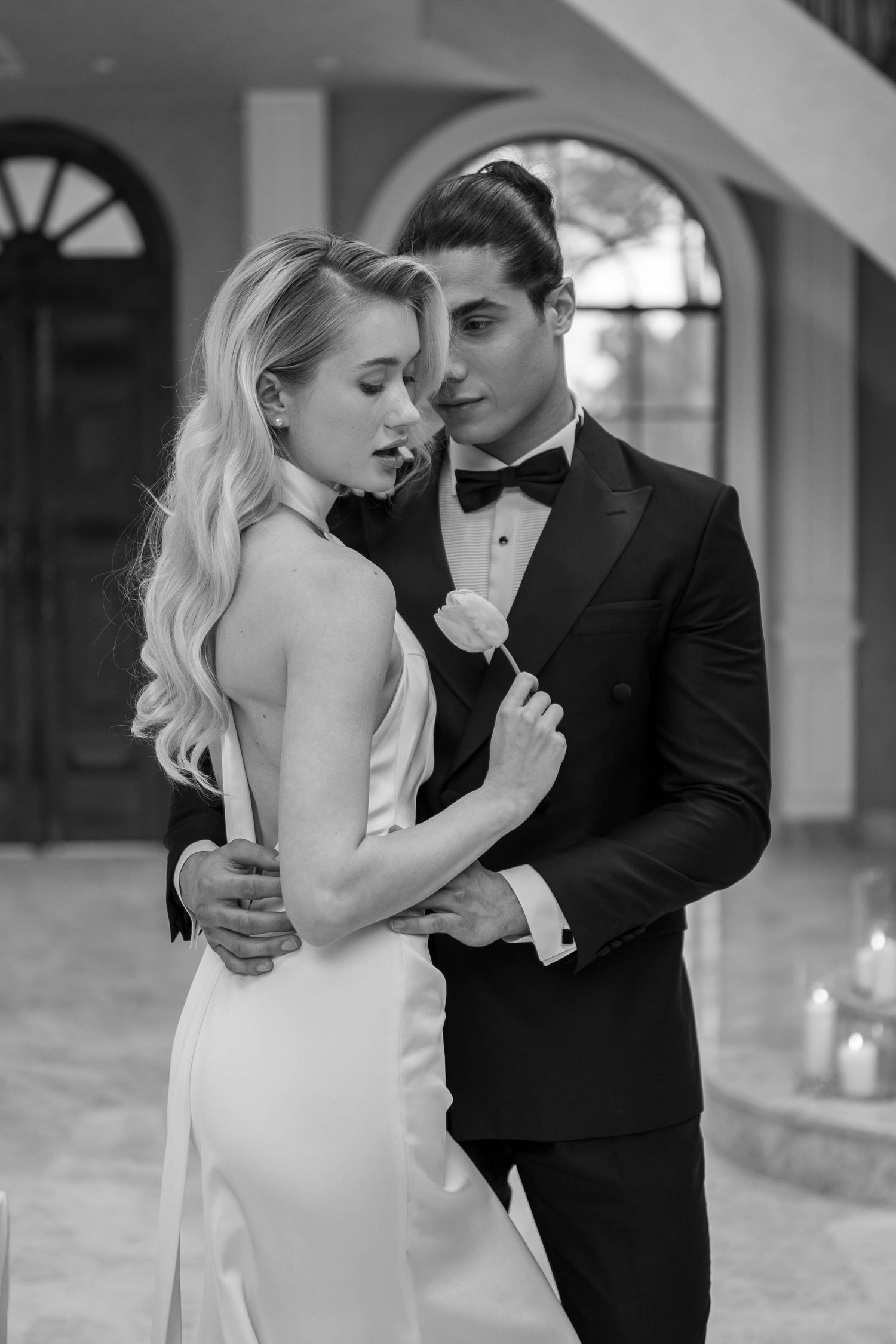 A romantic black and white wedding photo series showing a couple in formal attire dancing intimately together.