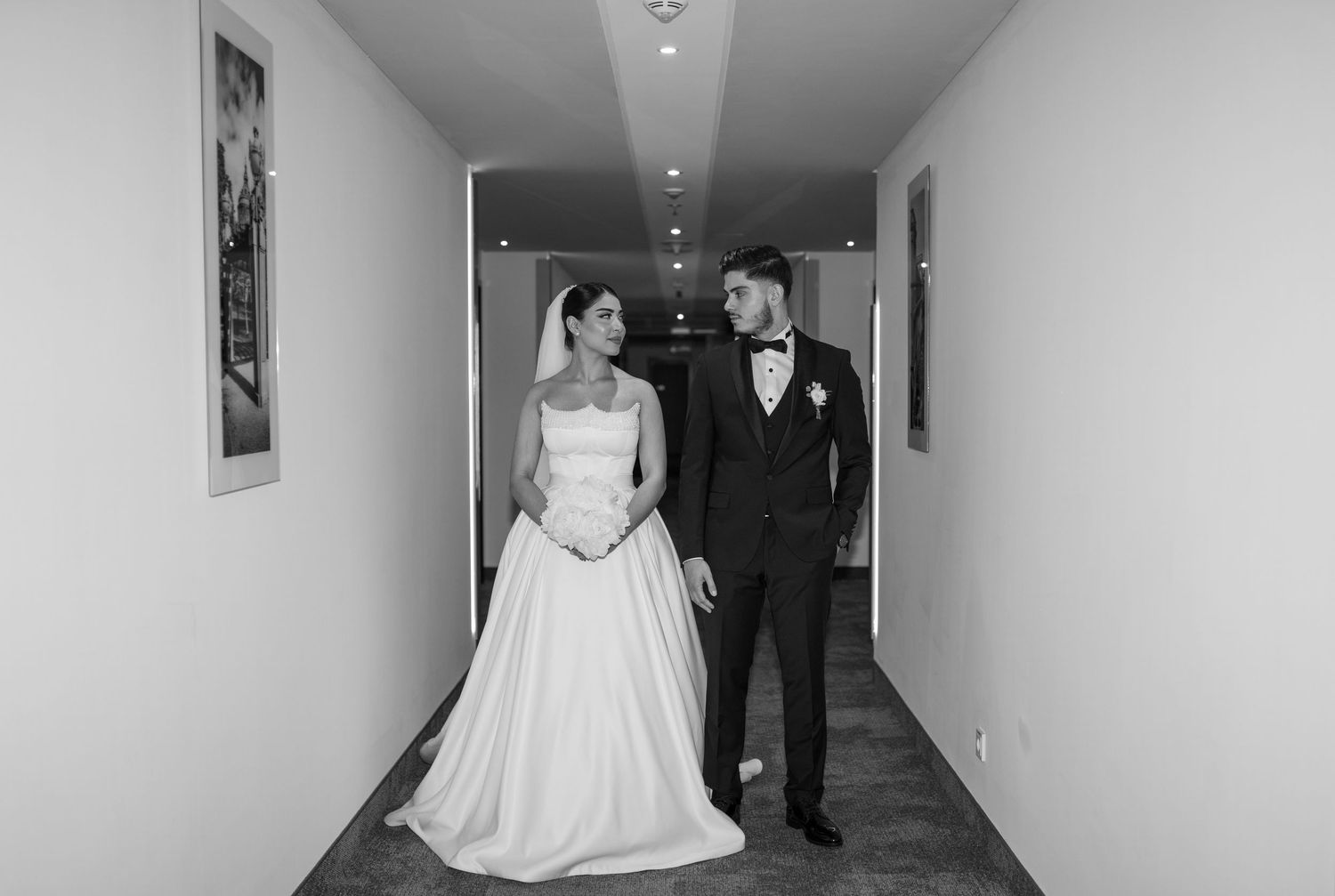 Sequence of black and white photos showing newlyweds walking down a bright corridor.