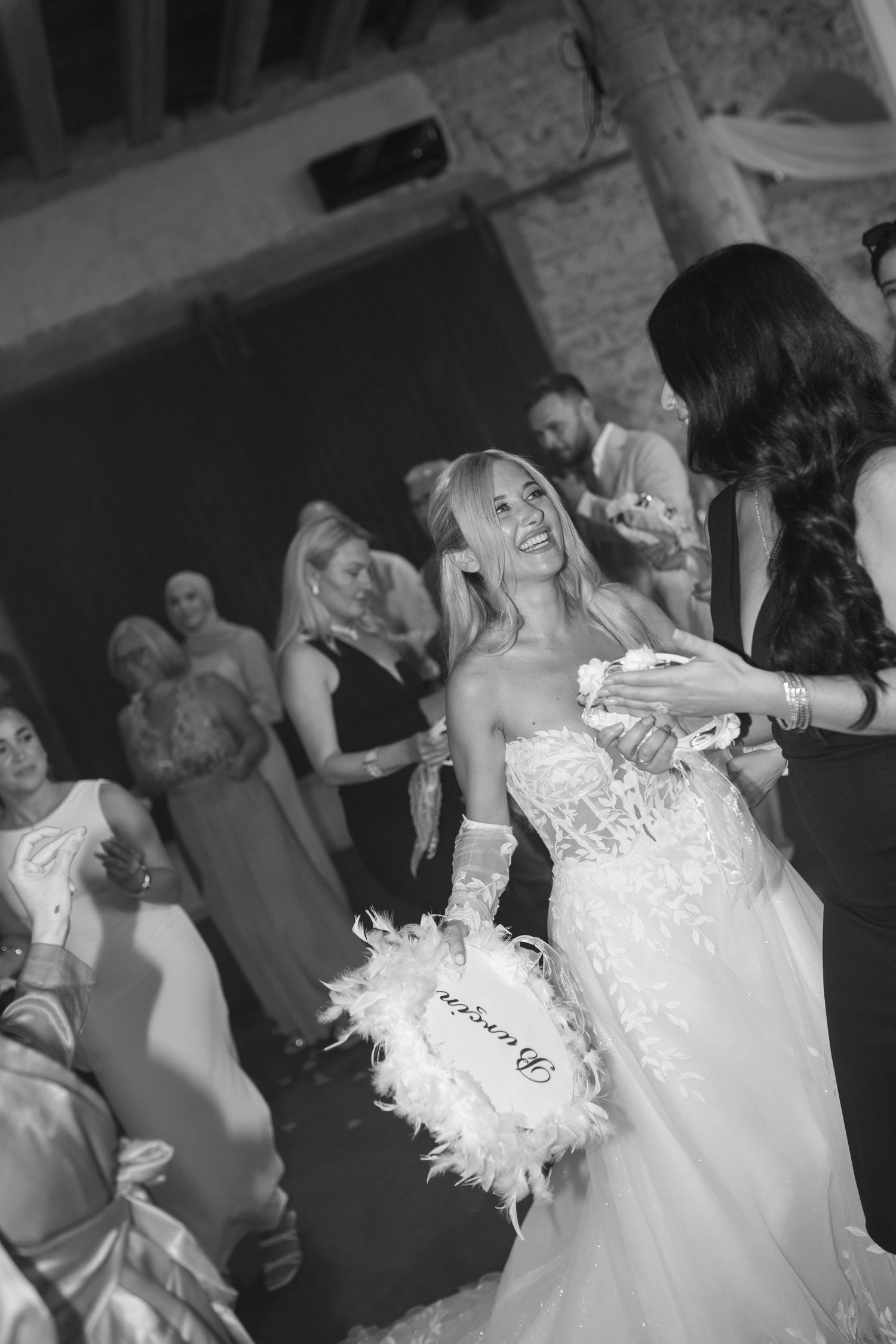 Wedding guests and newlyweds dancing energetically at a reception in a dimly lit venue.