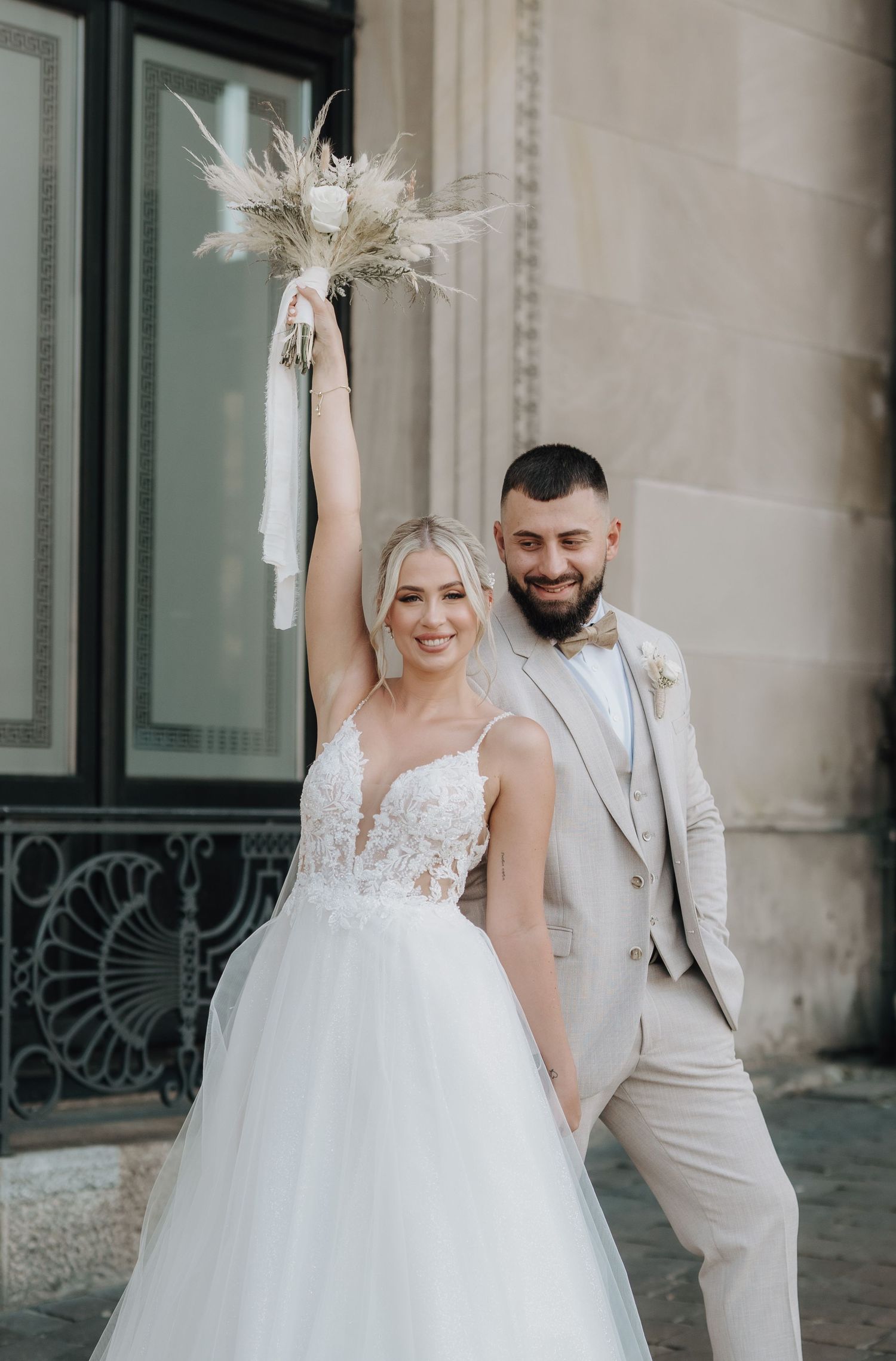 Brautpaar in elegantem Weiß vor Steinarchitektur – aufgenommen von Melér Wedding, Hochzeitsfotografen aus Deutschland.