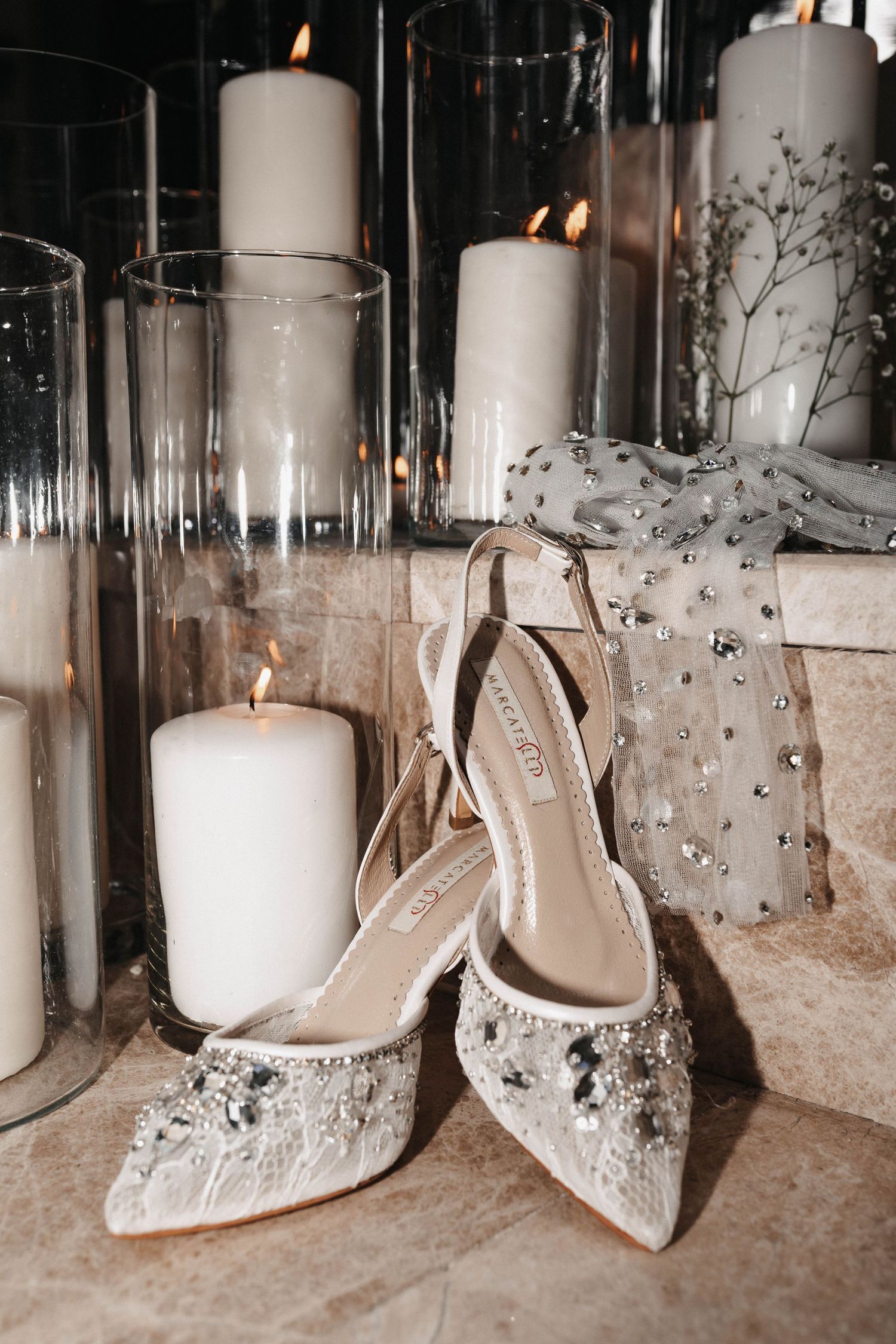 Wedding shoes displayed artistically among glass candle holders and white pillar candles.