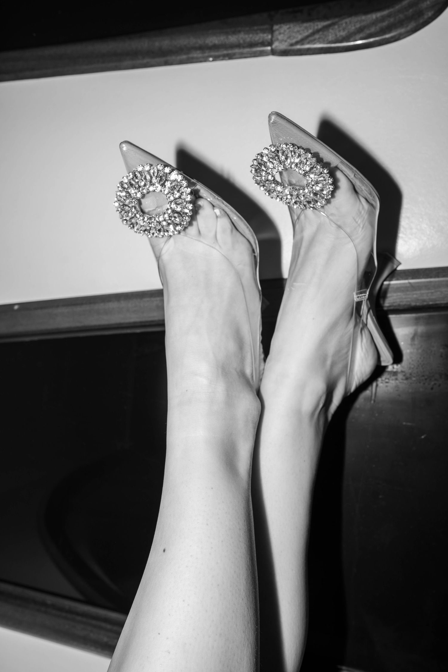 Elegant bridal shoes with crystal embellishments in black and white photography.