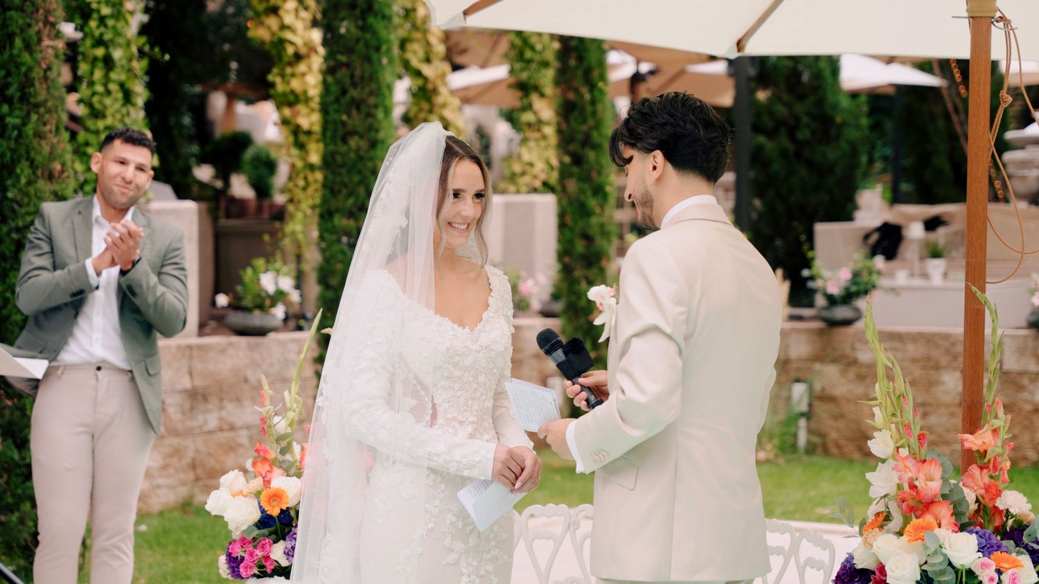 Wedding ceremony space decorated with white canopy and colorful floral arrangements.
