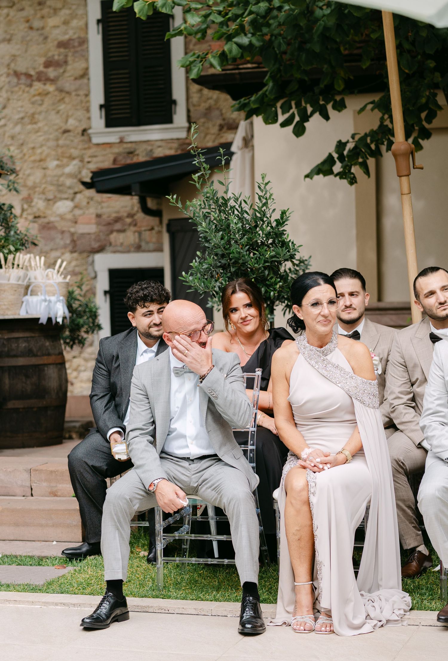 Wedding guests seated outdoors sharing emotional moments during ceremony.