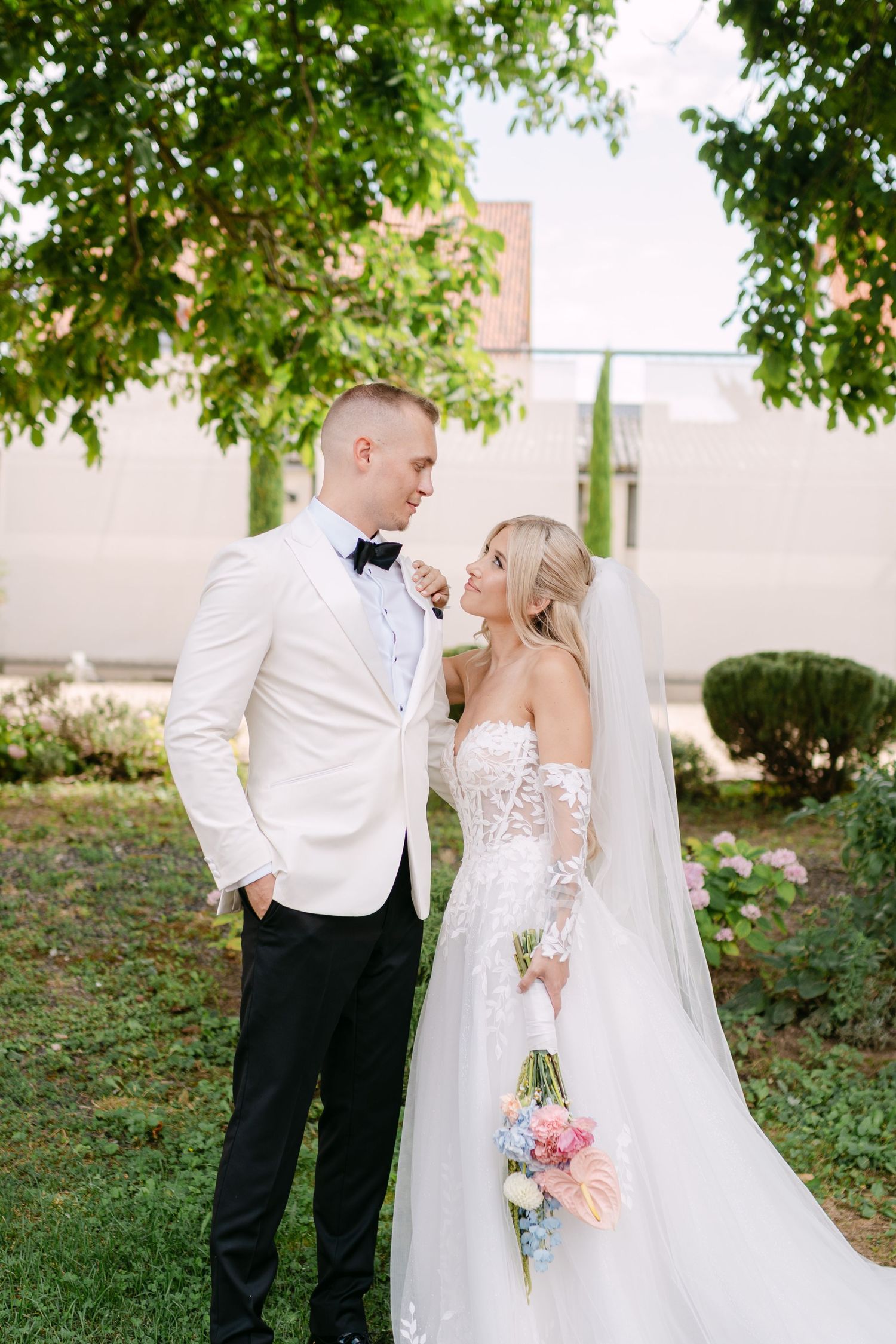 Newlyweds share candid moments together outdoors with lush greenery in the background.