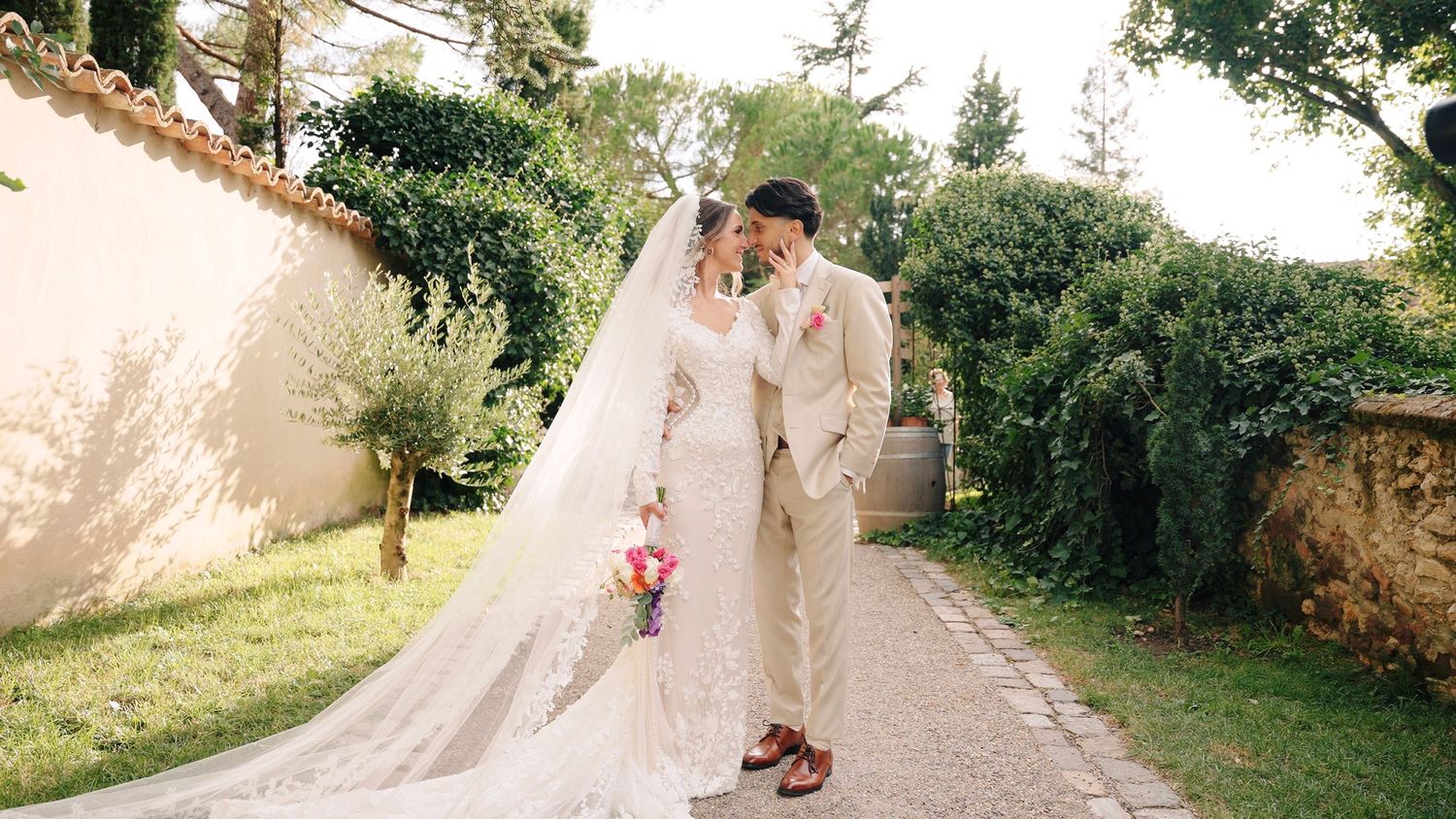 Panoramic wedding scene along a garden pathway with scattered flower petals.