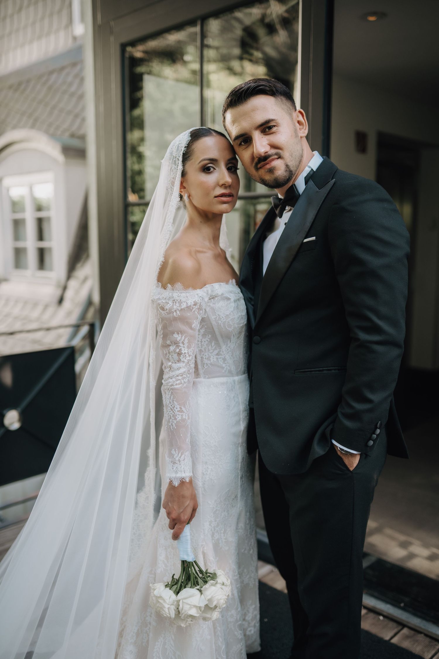 Romantic outdoor wedding portrait with elegant white gown and classic black tuxedo.