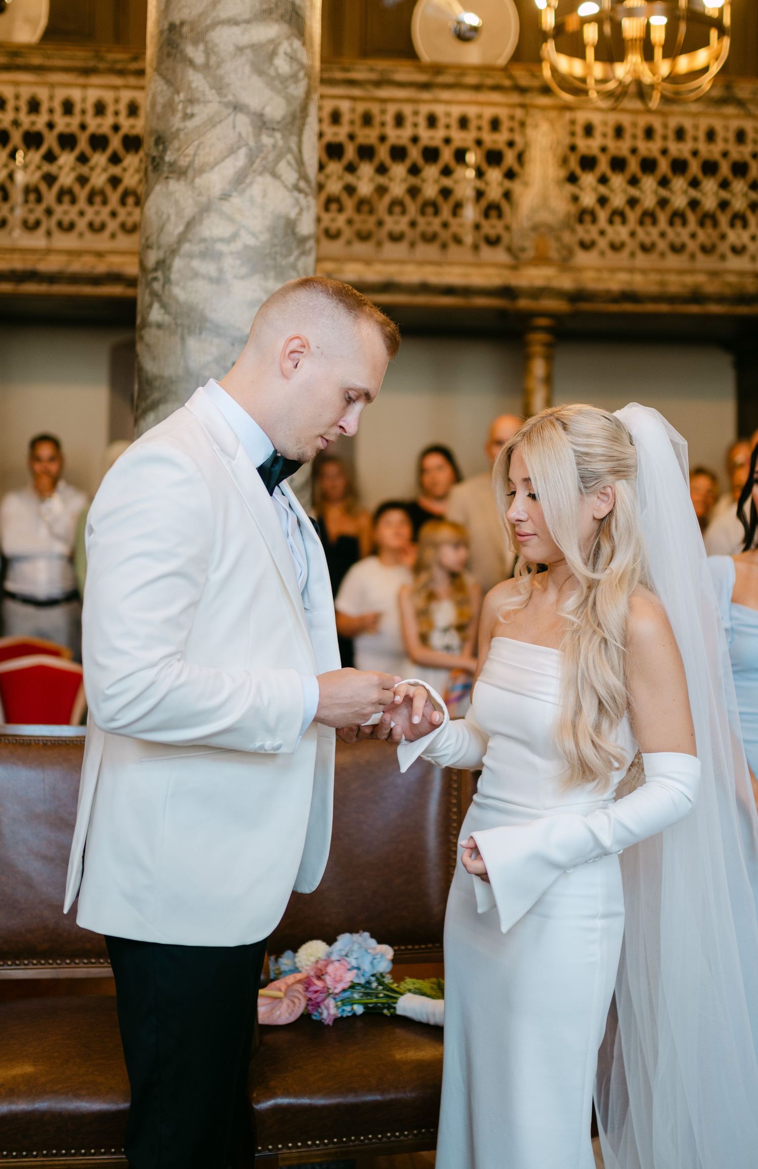 Couple shares an intimate dance moment in an ornate ballroom with decorative ceiling details.