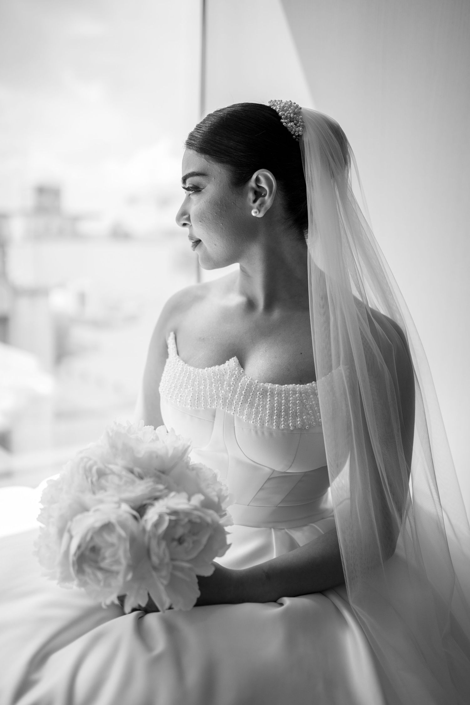 Black and white portrait series of a bride in a white gown holding a bouquet near a window.
