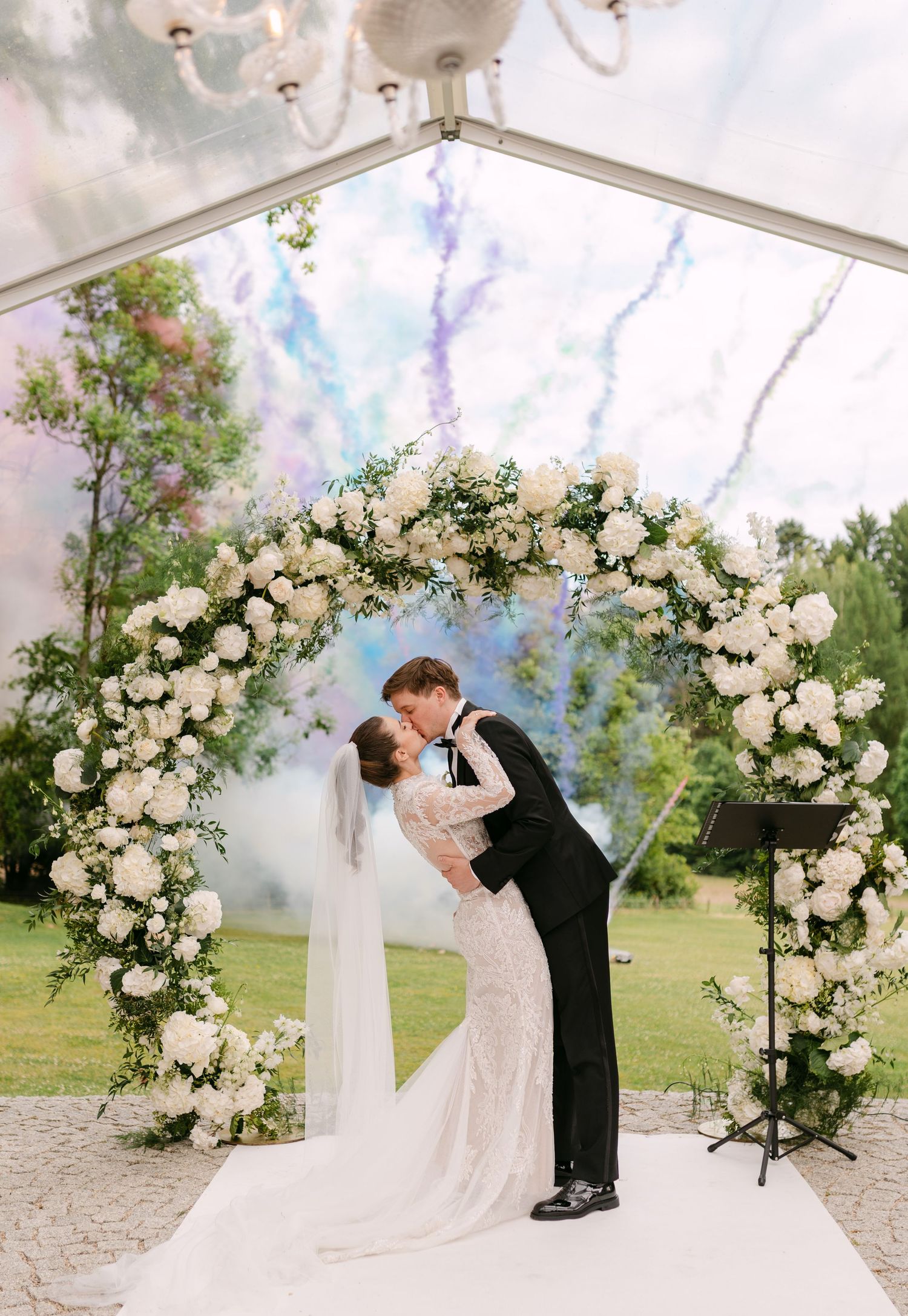 Romantic wedding ceremony under floral arch with white roses and elegant draping.