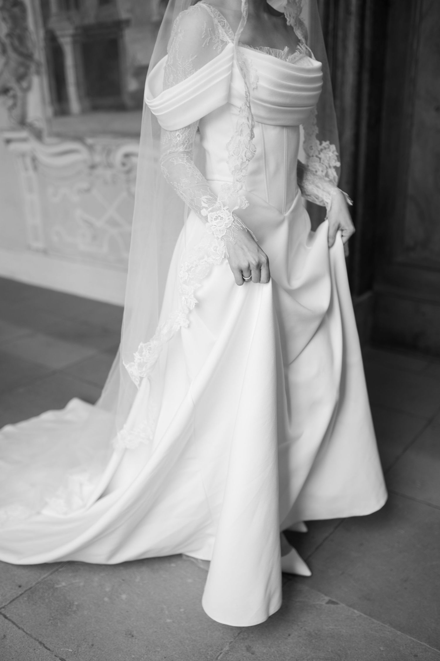 Detail shots of a flowing white wedding dress train and hem against a stone floor.
