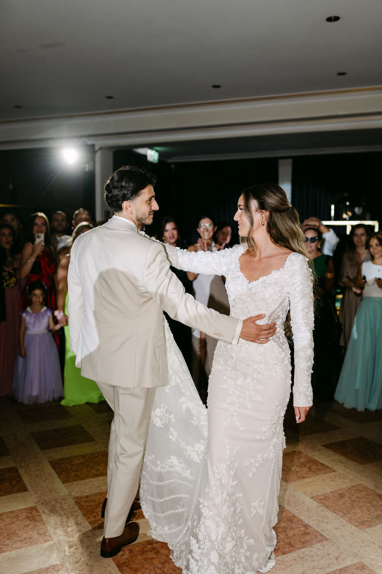 Couple dancing together at their wedding reception surrounded by guests.