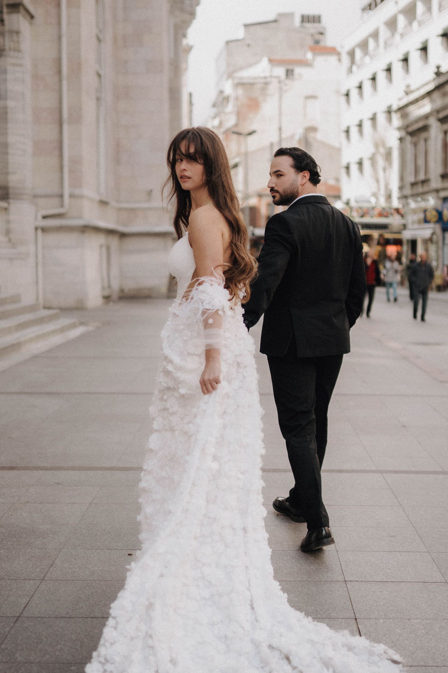 Couple walking through historic city streets with flowing white dress.