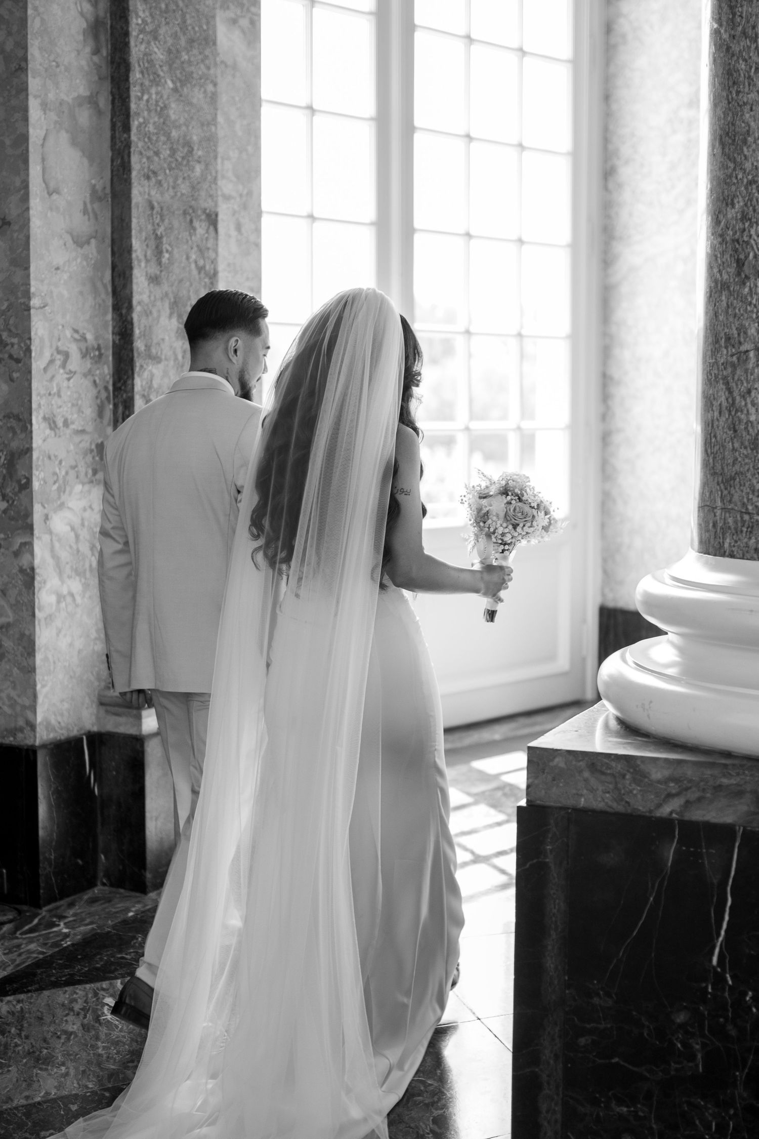 Brautpaar im hellen Marmorsaal mit klassischer Architektur – moderne Hochzeitsreportage von Melér Wedding.
