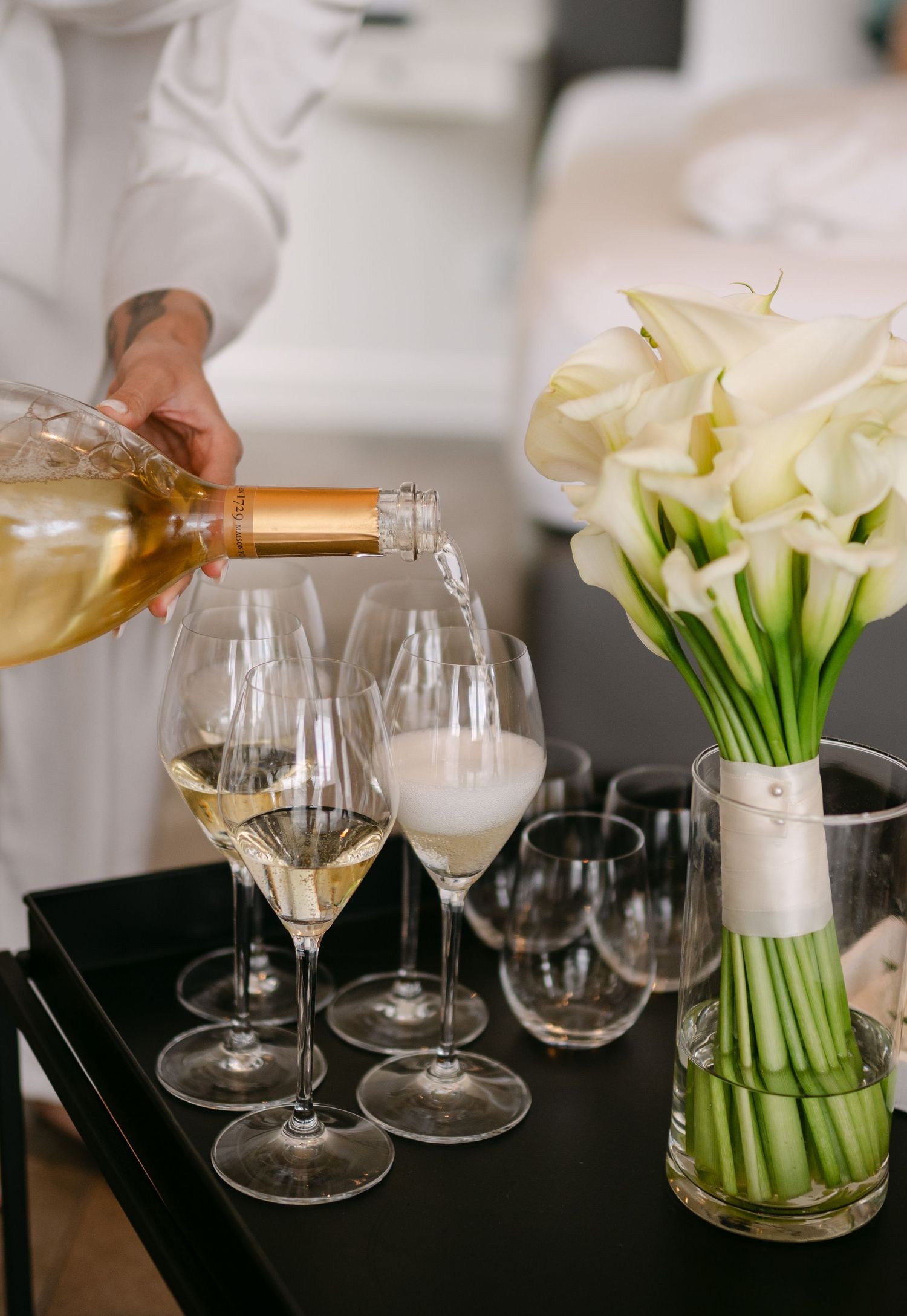 Elegant table setting with white calla lilies and wine glasses being served.