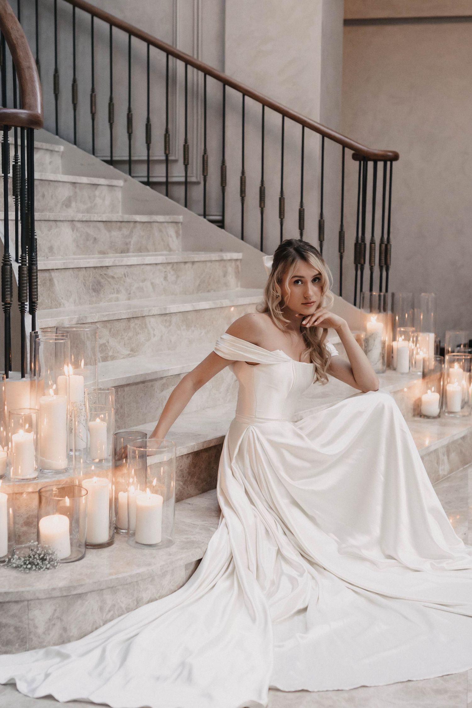 Elegant bridal portraits on stairs with glowing candles creating romantic ambiance.