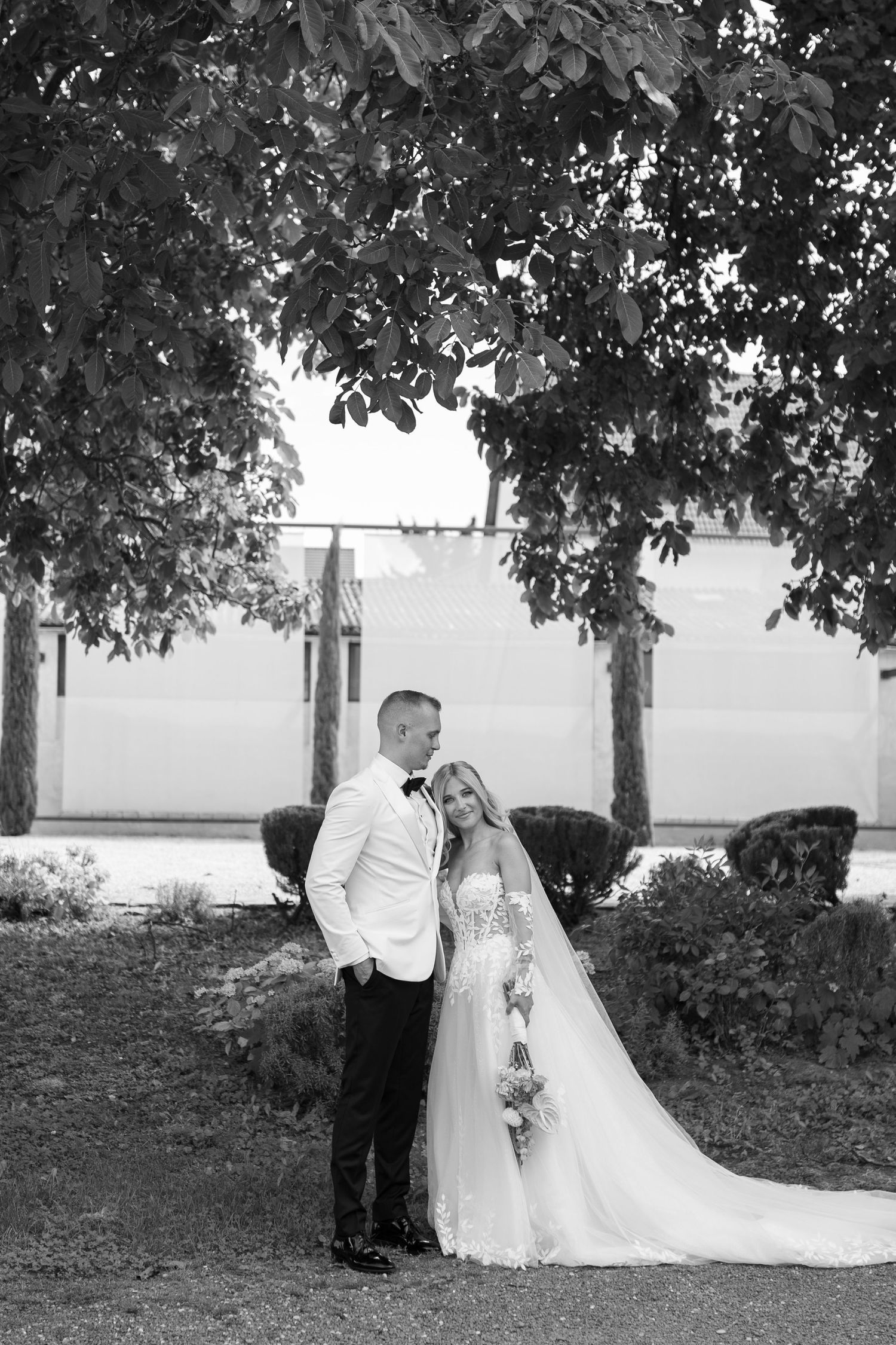 A romantic black and white wedding photo sequence showing a couple posing under trees.