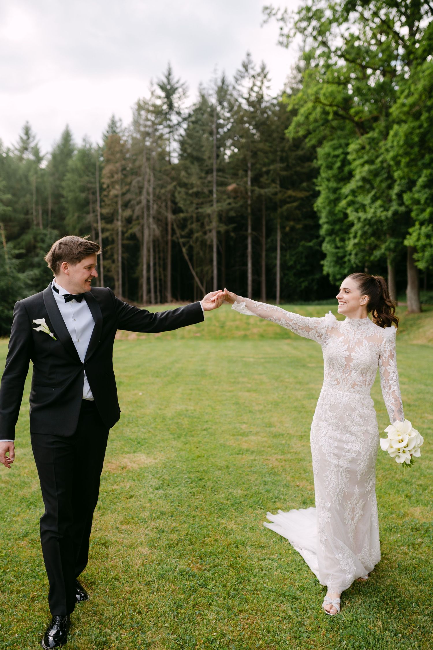 Couple dances and twirls across a scenic grassy field during their wedding celebration.
