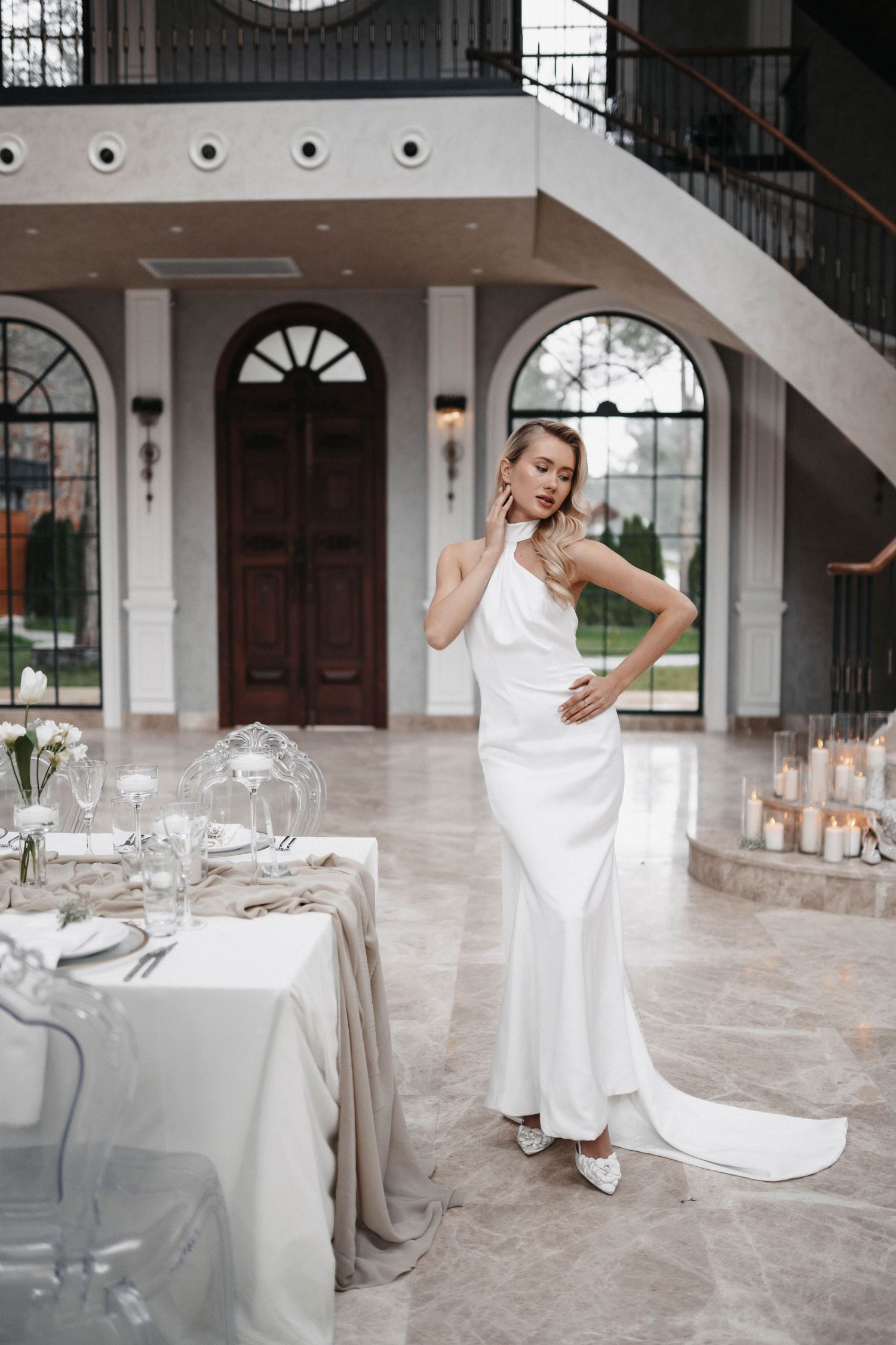 Modern wedding reception setup with elegant place settings and candles in a bright venue.