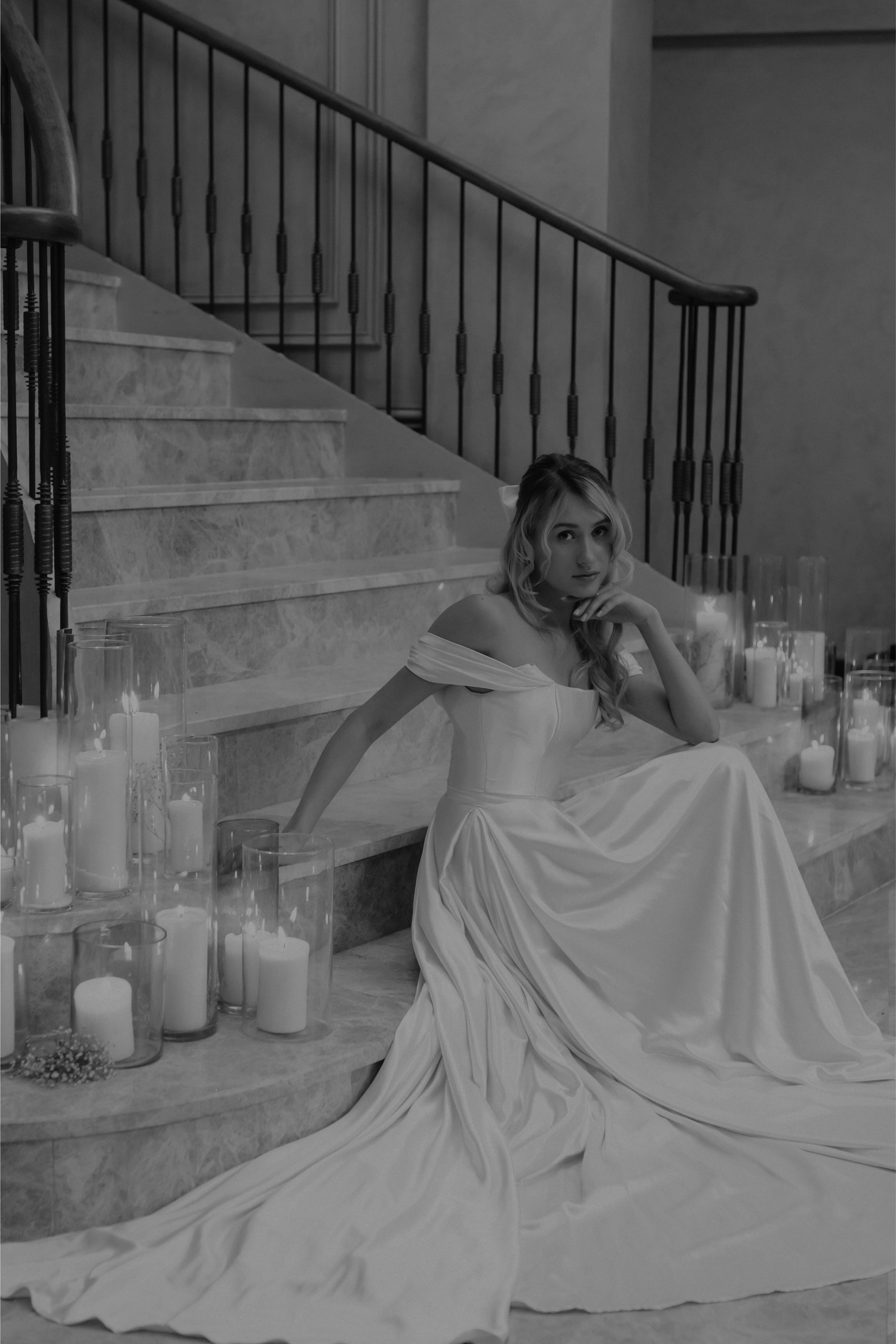 Black and white bridal portraits on stairs surrounded by lit candles.