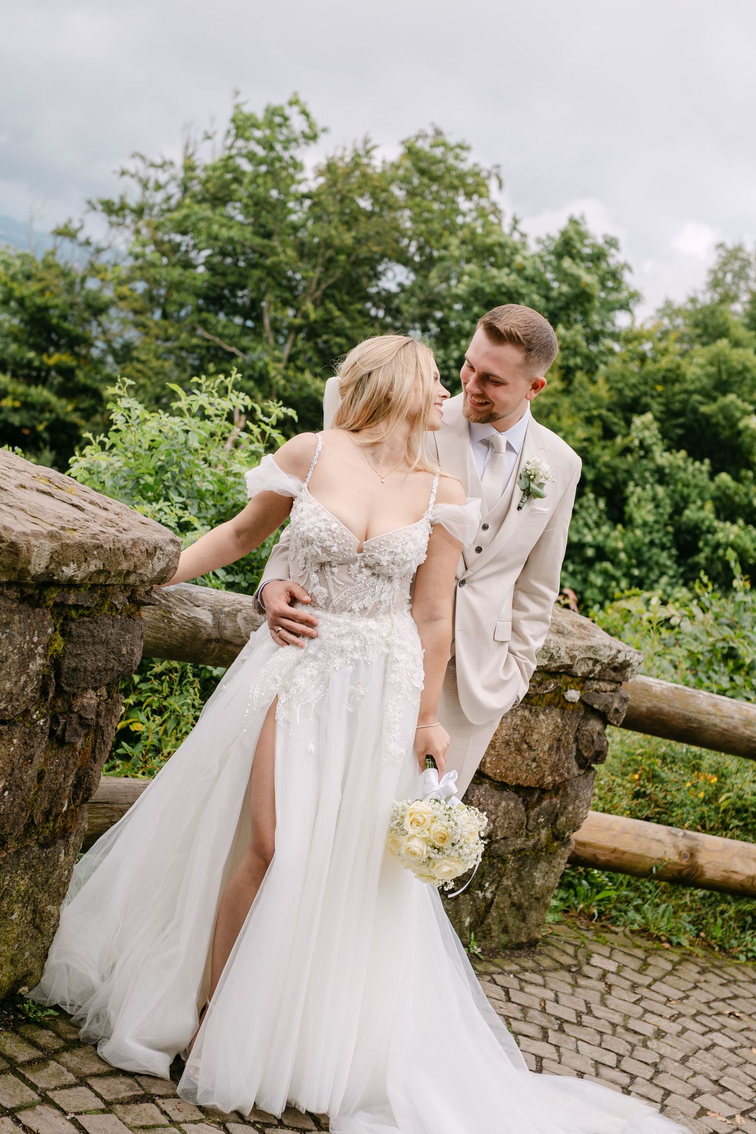 Romantic wedding portraits by a rustic wooden fence with mountain views in the background.