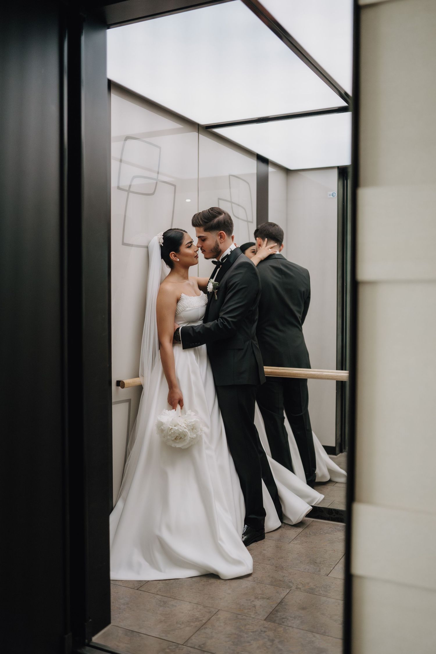 Intimate wedding couple moment captured through mirror reflections in minimalist space.