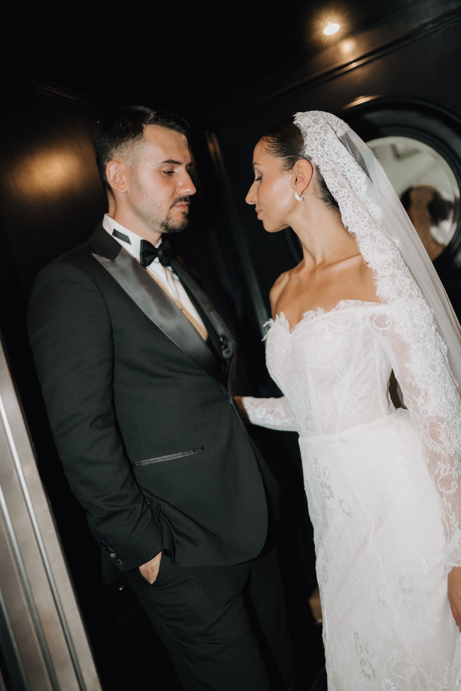 Dramatic low-light wedding photo showing intimate moment between couple in formal attire.
