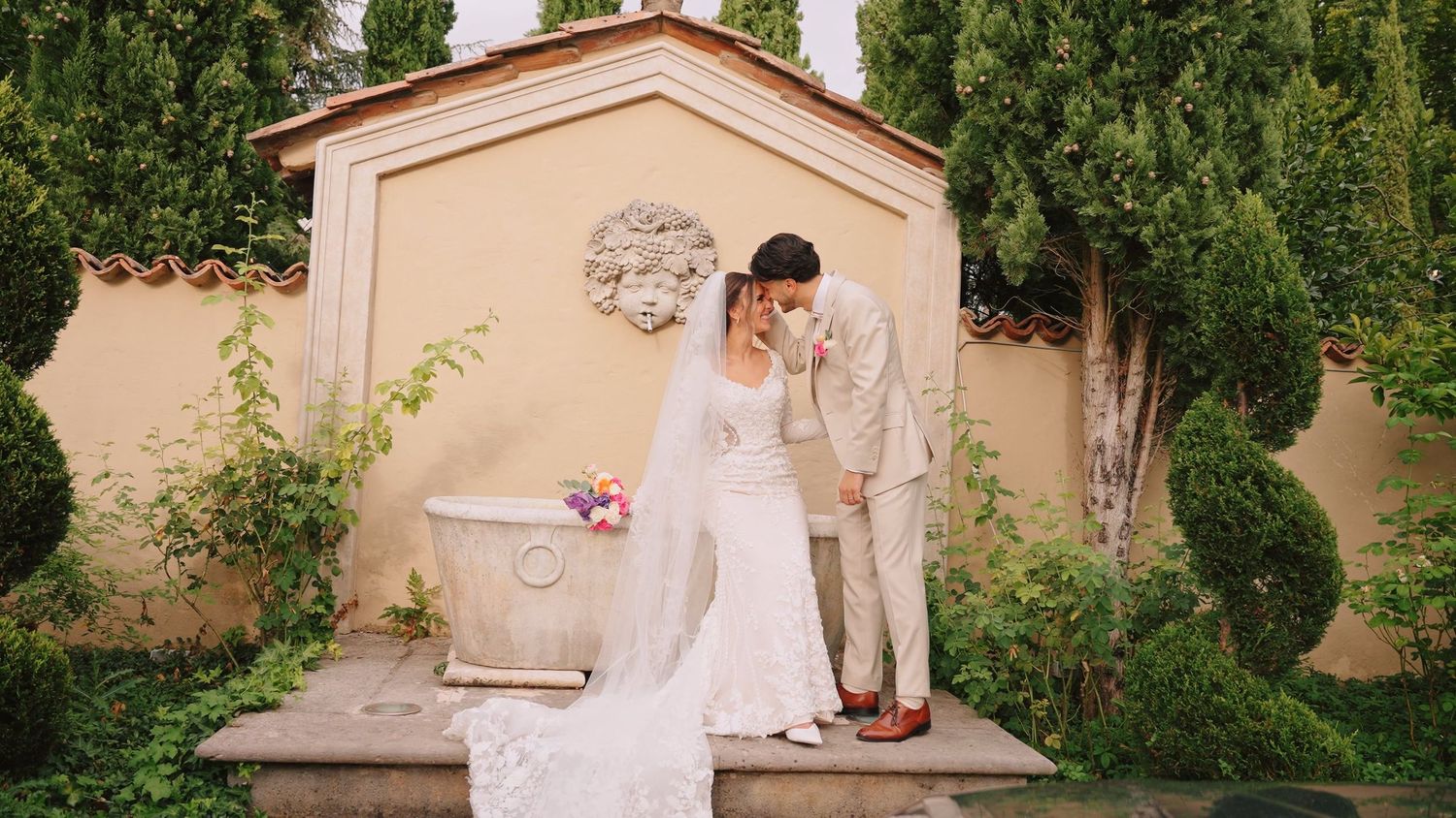 Elegant outdoor wedding ceremony setup with white chairs and floral arrangements in a lush garden setting.