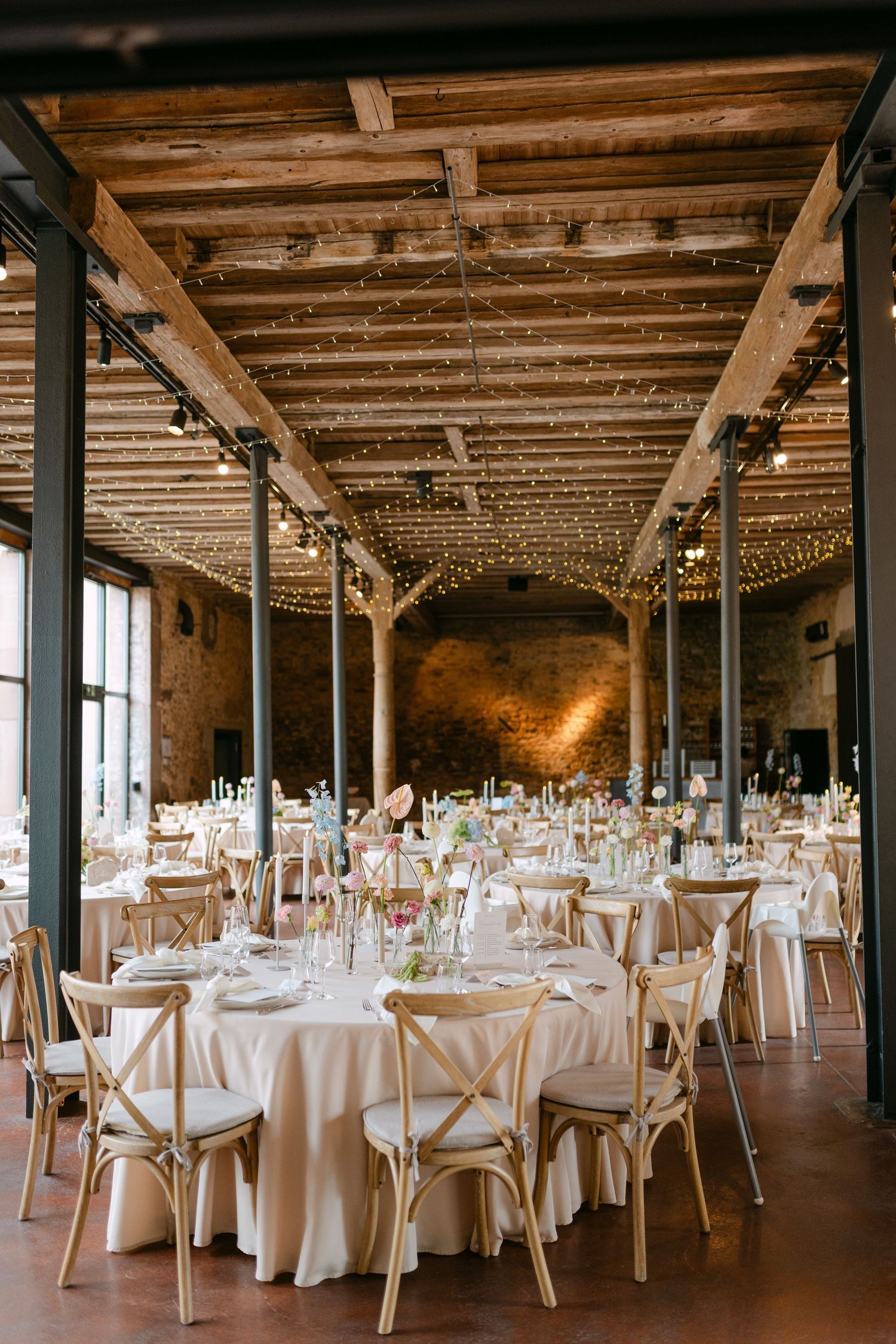 Rustic wedding reception venue with exposed wooden beams and white table settings.