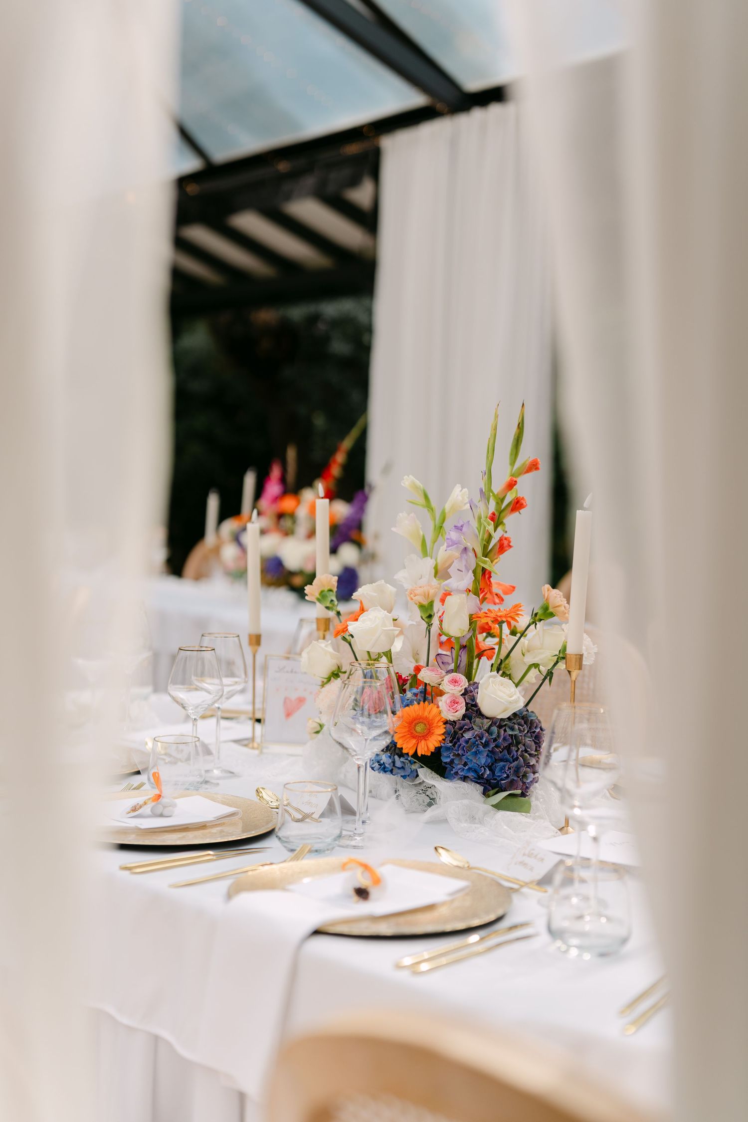 Wedding table settings with colorful floral arrangements and elegant glassware.