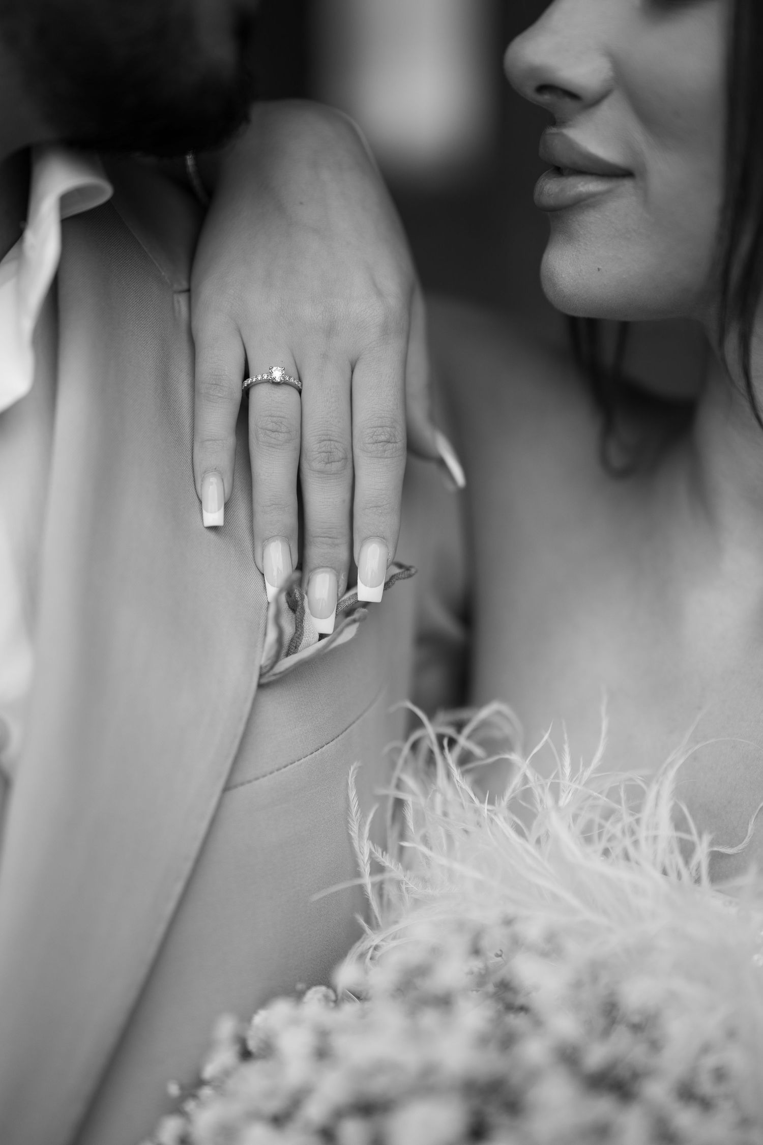 Close-up of wedding rings and manicured hands with a soft-focus bouquet.