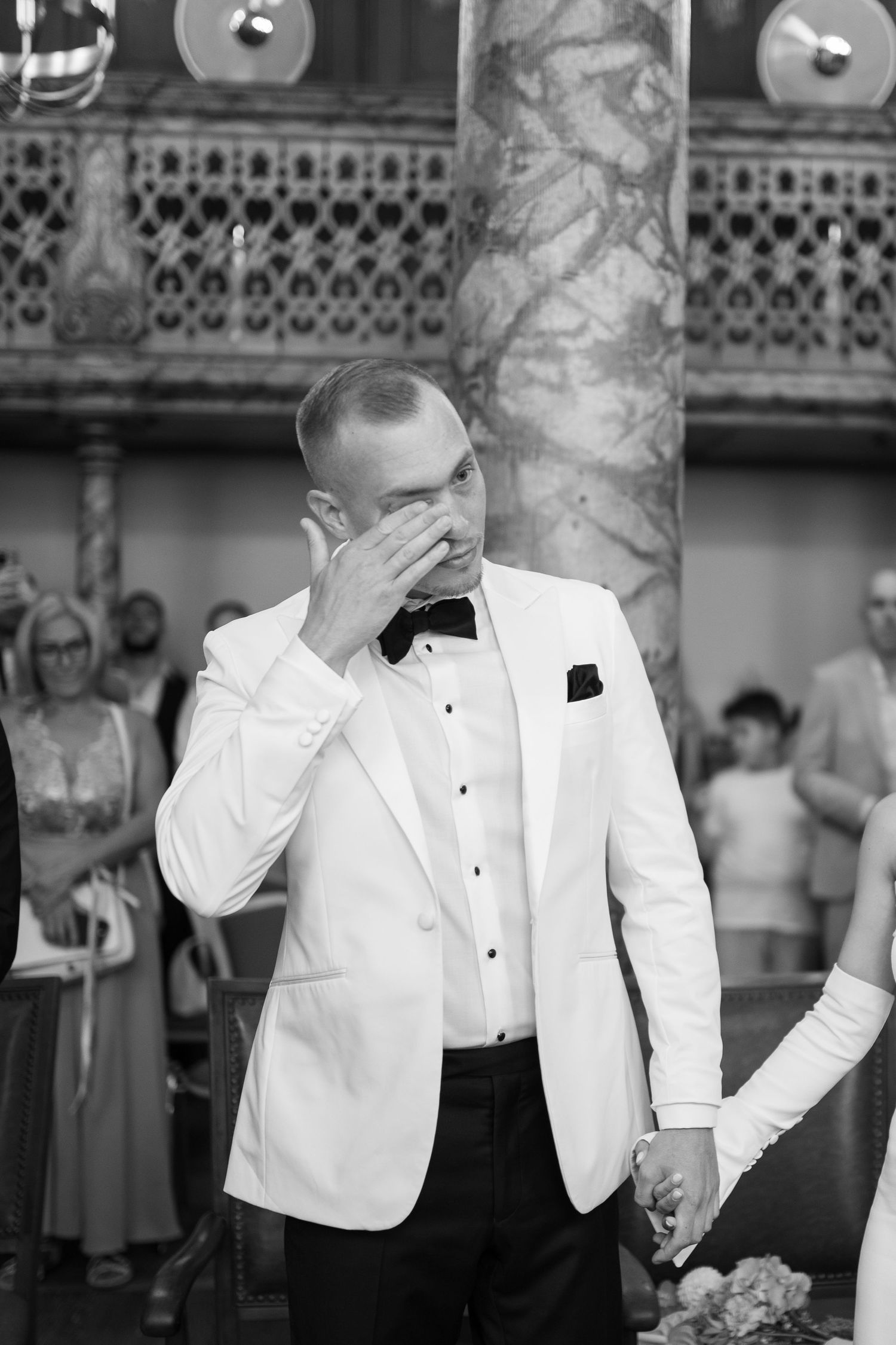 Person in white tuxedo jacket showing emotional reactions in a formal setting.