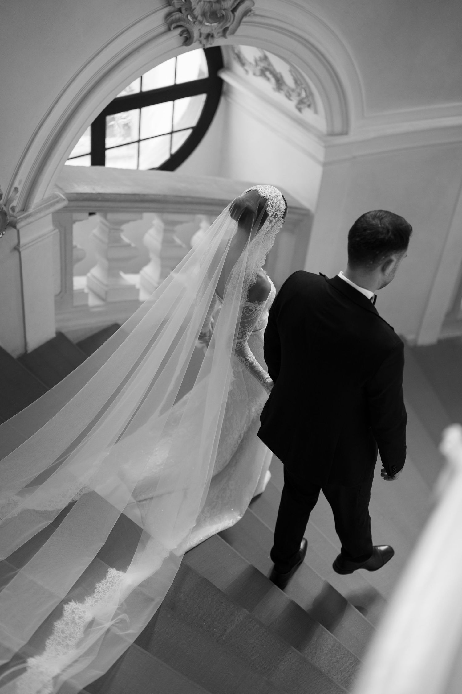 Black and white sequence showing couple ascending elegant curved stairs in formal attire.