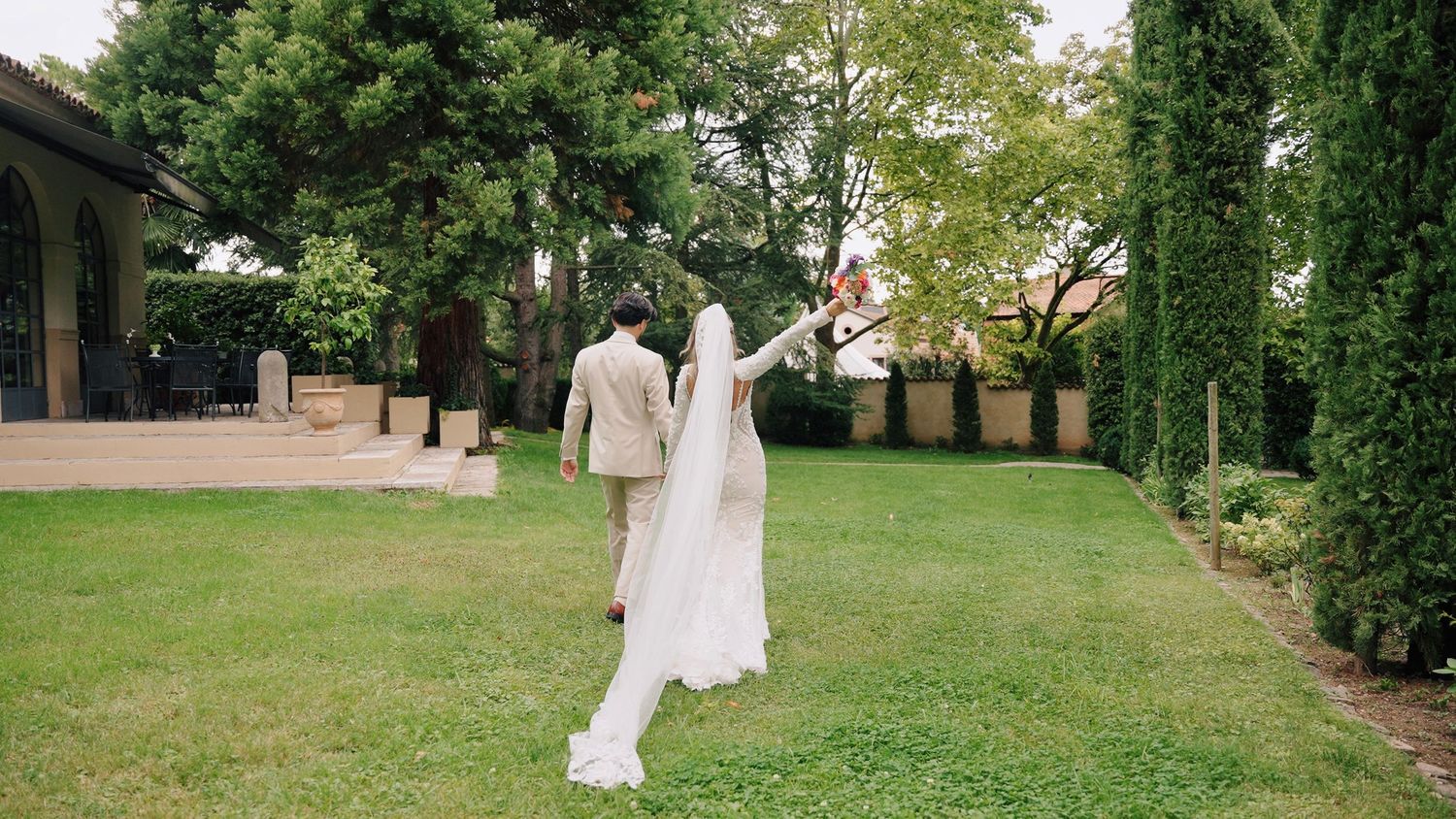 Wedding celebration in an elegant garden setting with Mediterranean architecture.