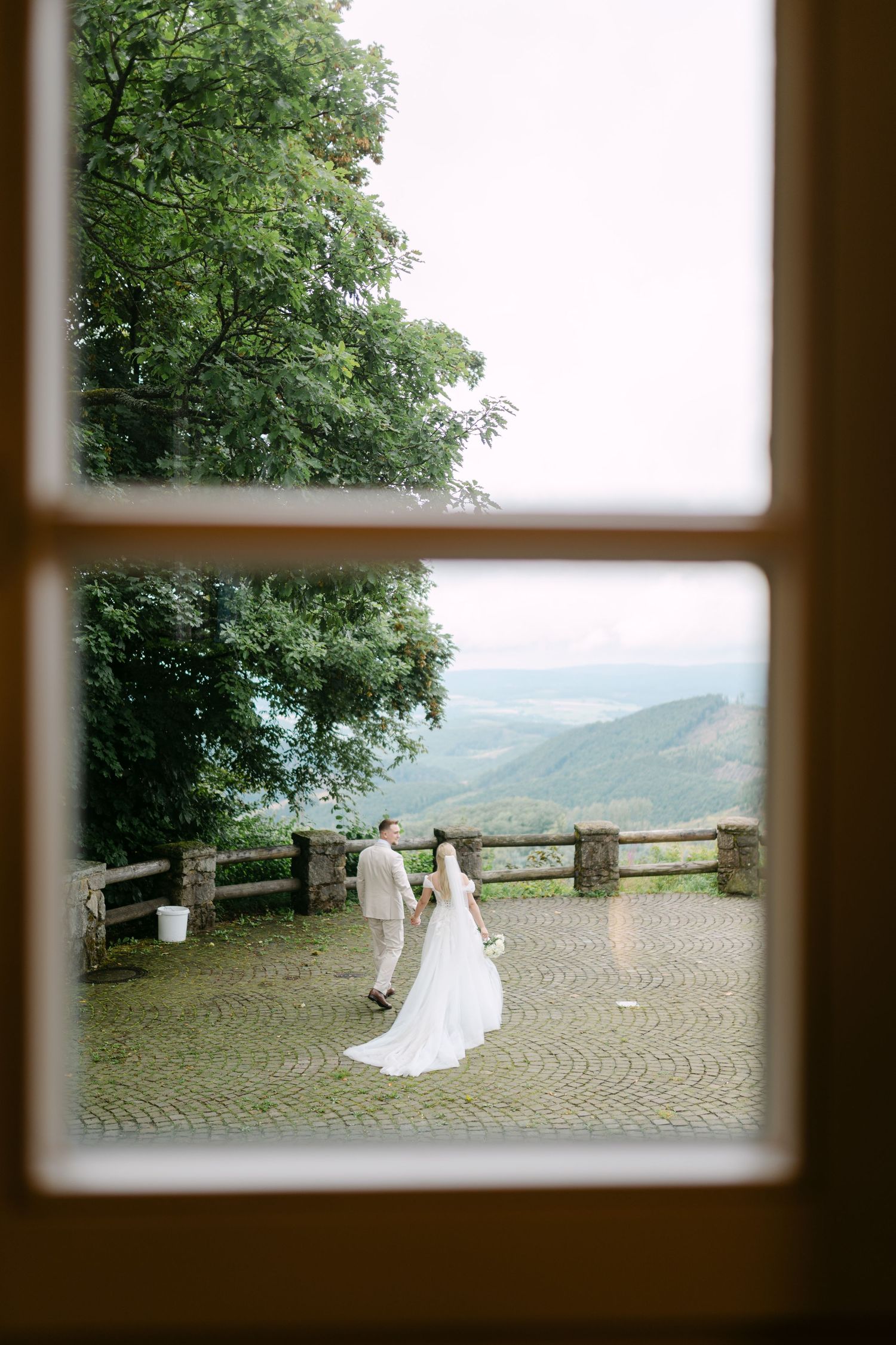 View through window panes of a wedding couple on a scenic mountain terrace.