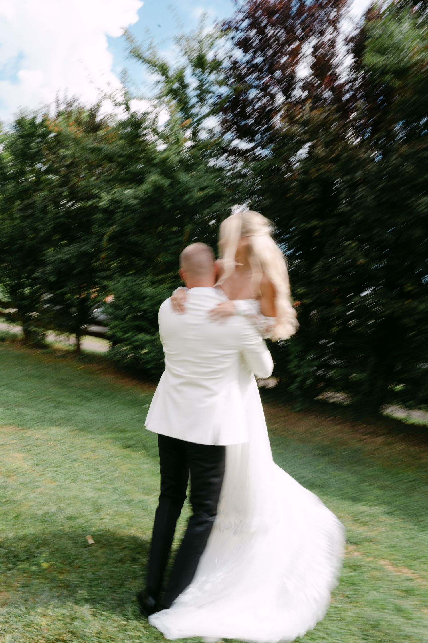 Wedding couple spins and dances together in a blurred motion sequence outdoors.