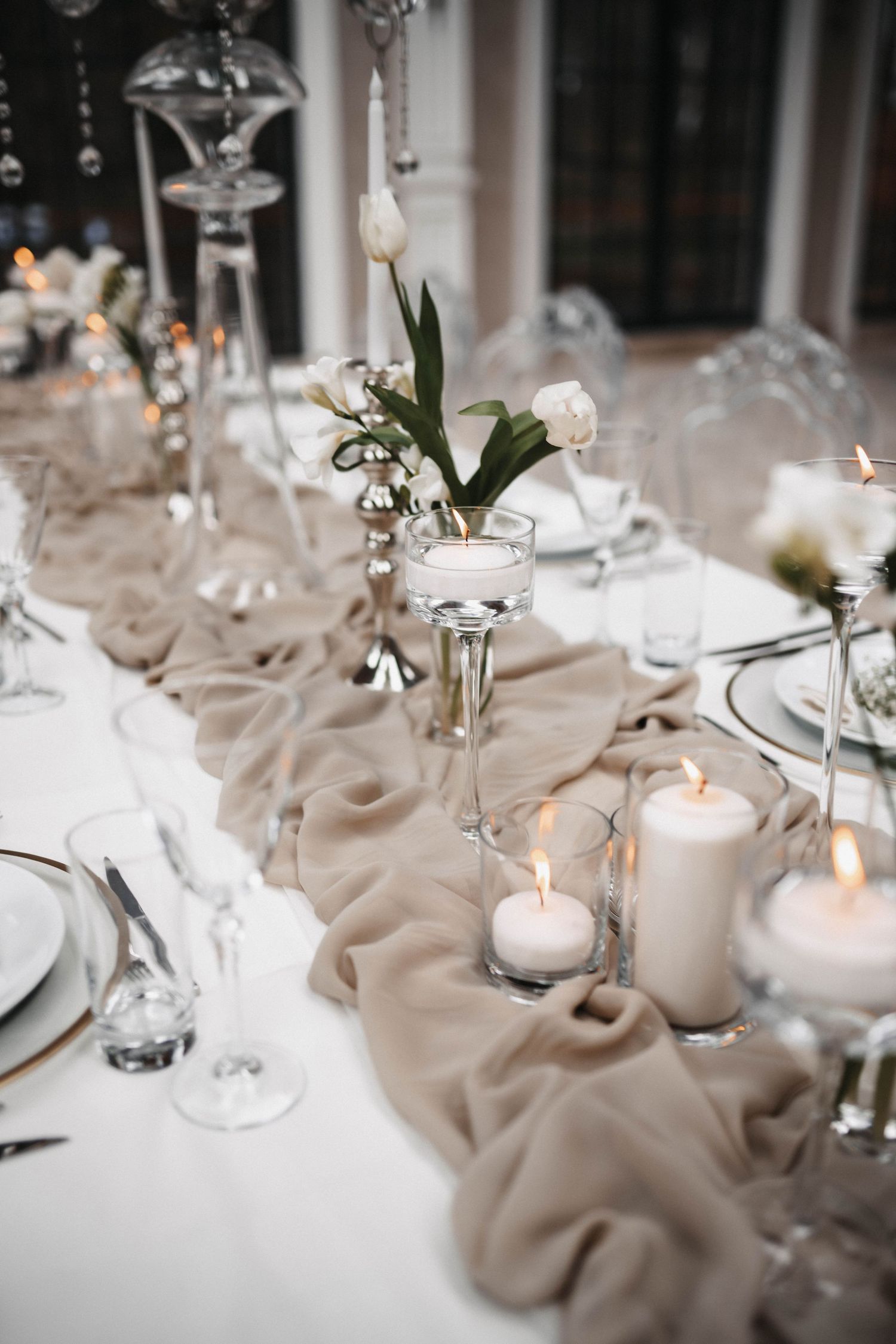 Elegant wedding table setting with white candles, flowers and draped fabric creating a romantic atmosphere.