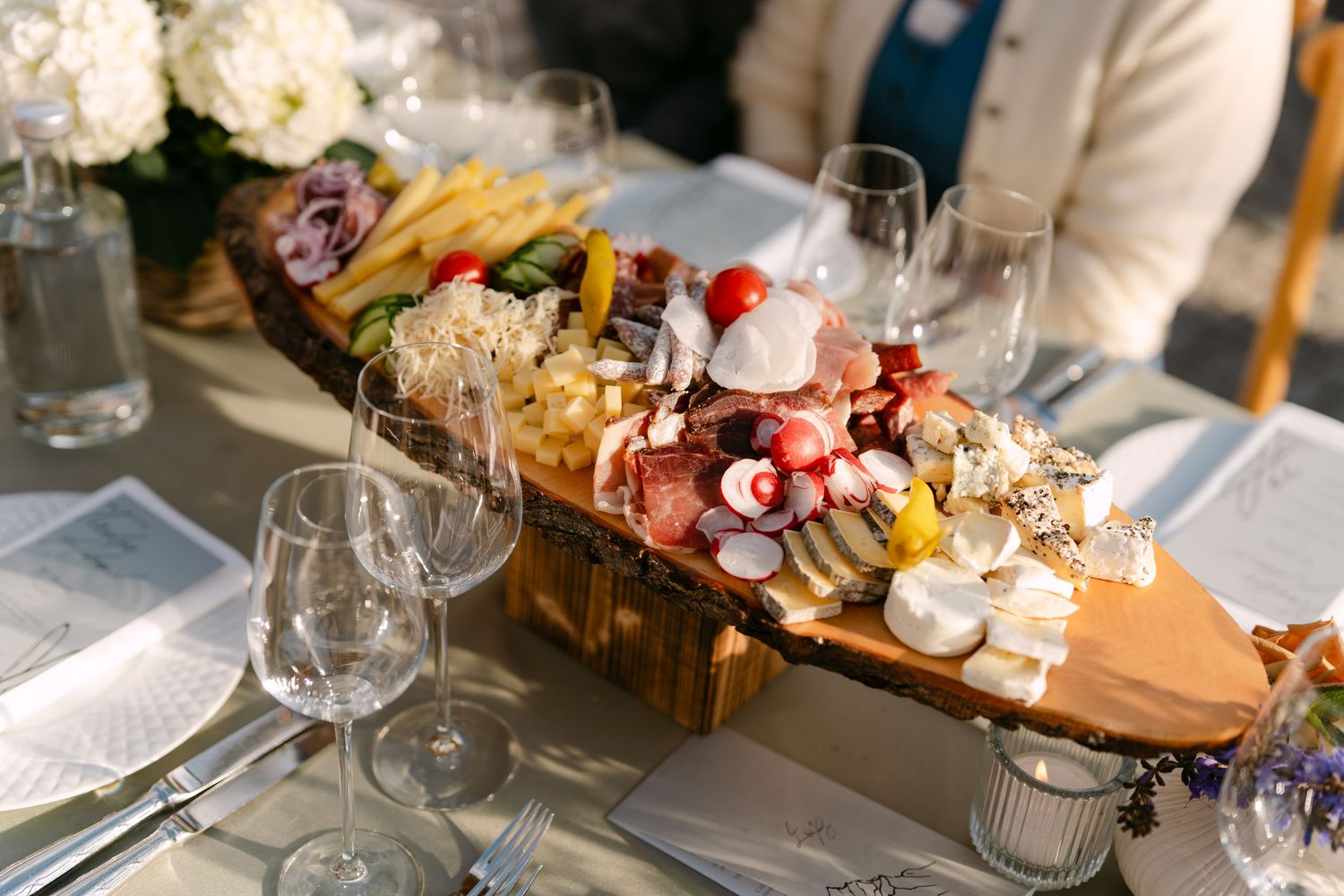 Elegant wedding reception table with charcuterie boards and wine glasses.