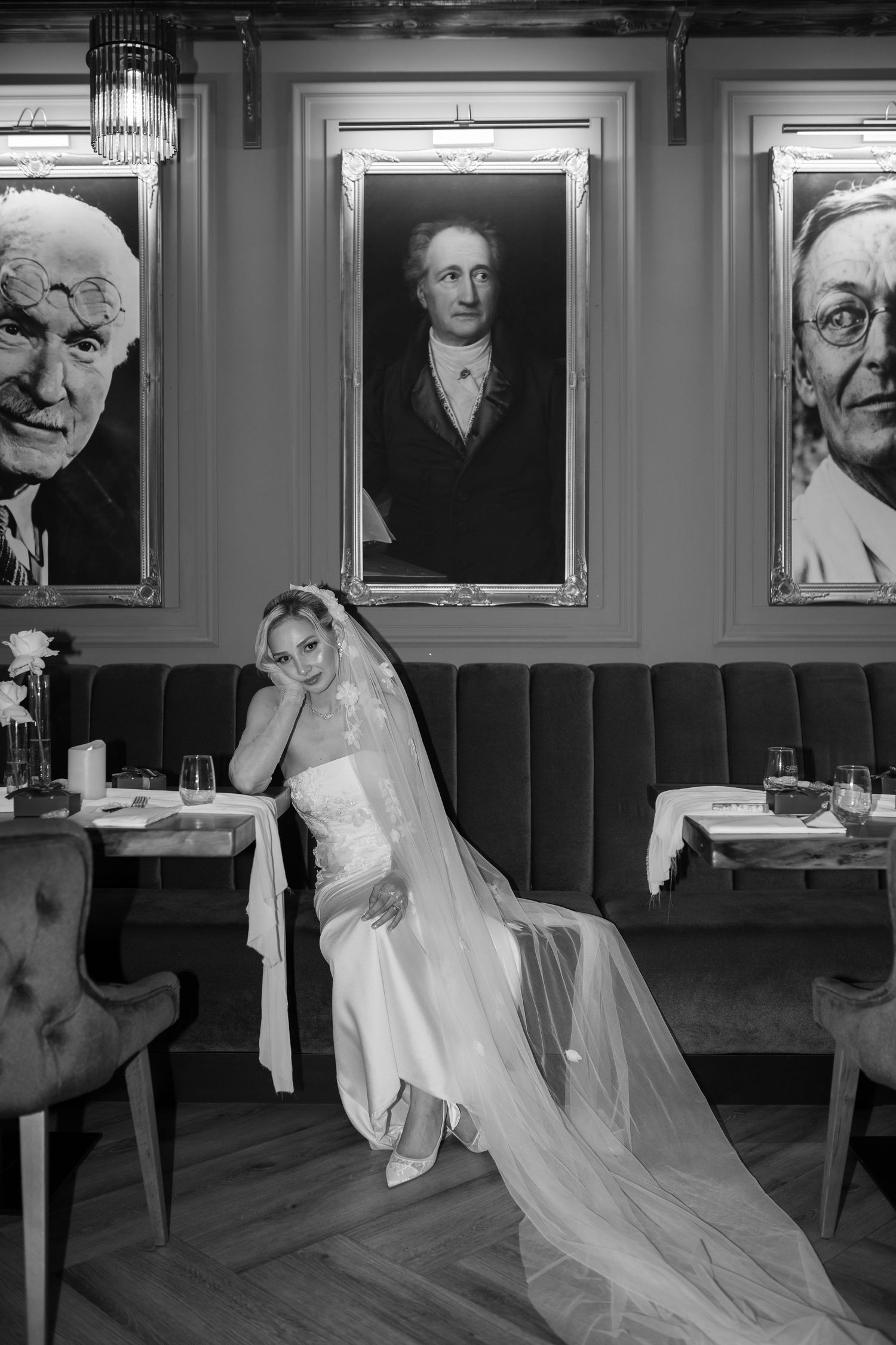Artistic black and white sequence showing flowing white fabric movement against portrait-lined wall.