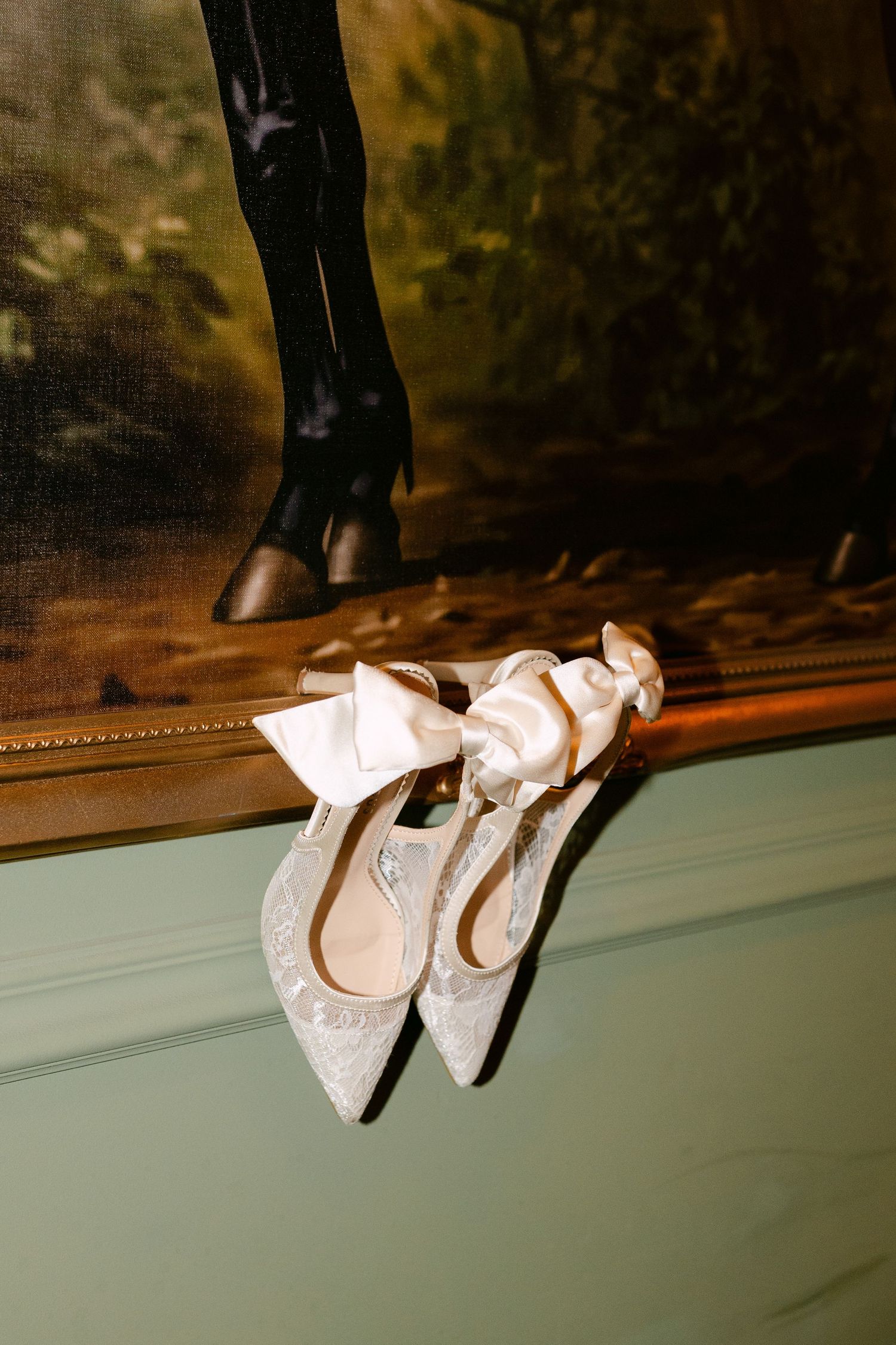 Wedding shoes displayed artistically on a ledge with dramatic lighting and shadows.