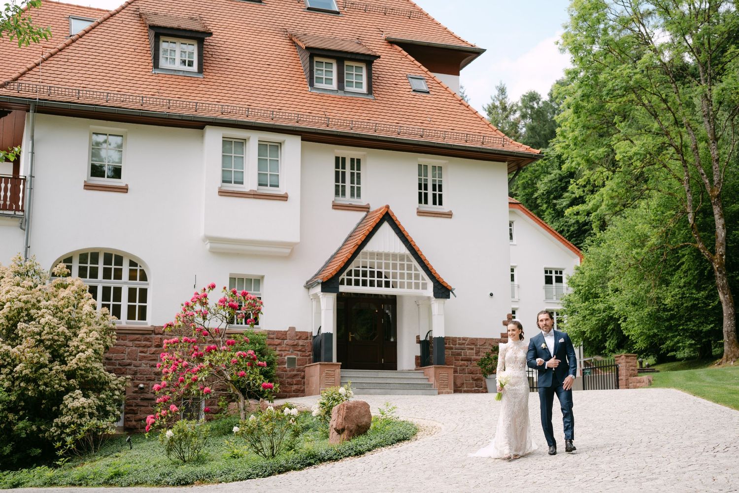 Elegant brick house exterior with white trim and garden landscaping.