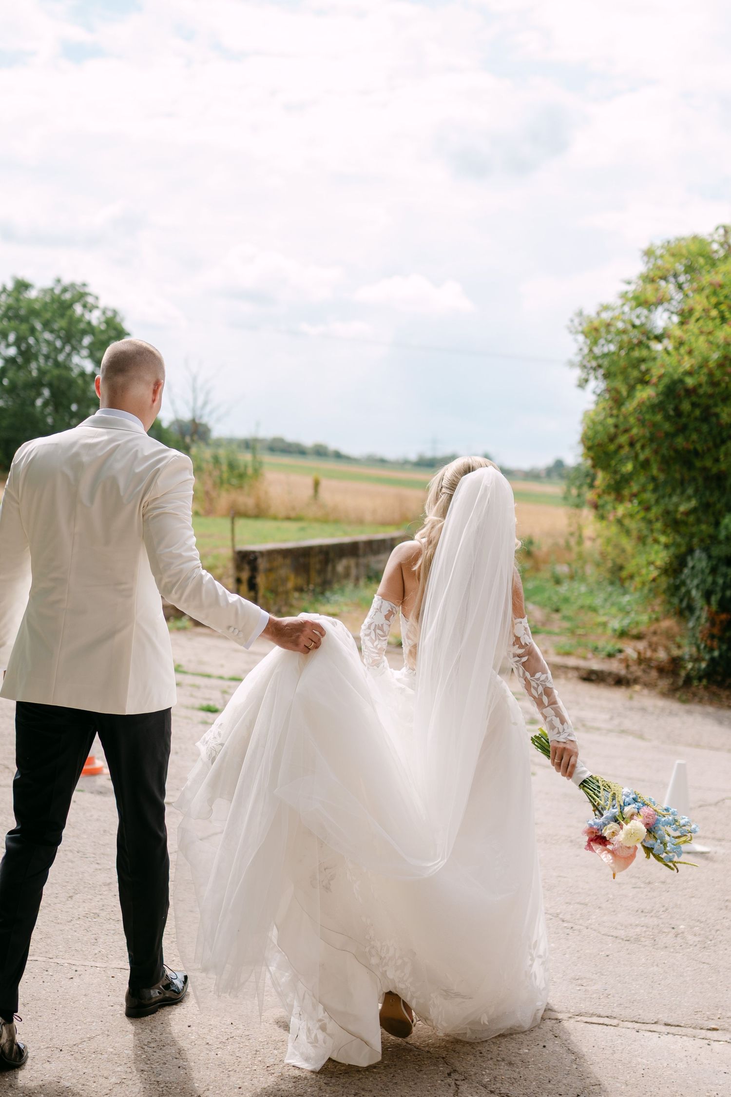 Wedding couple walking and posing on a country path with flowing white dress.
